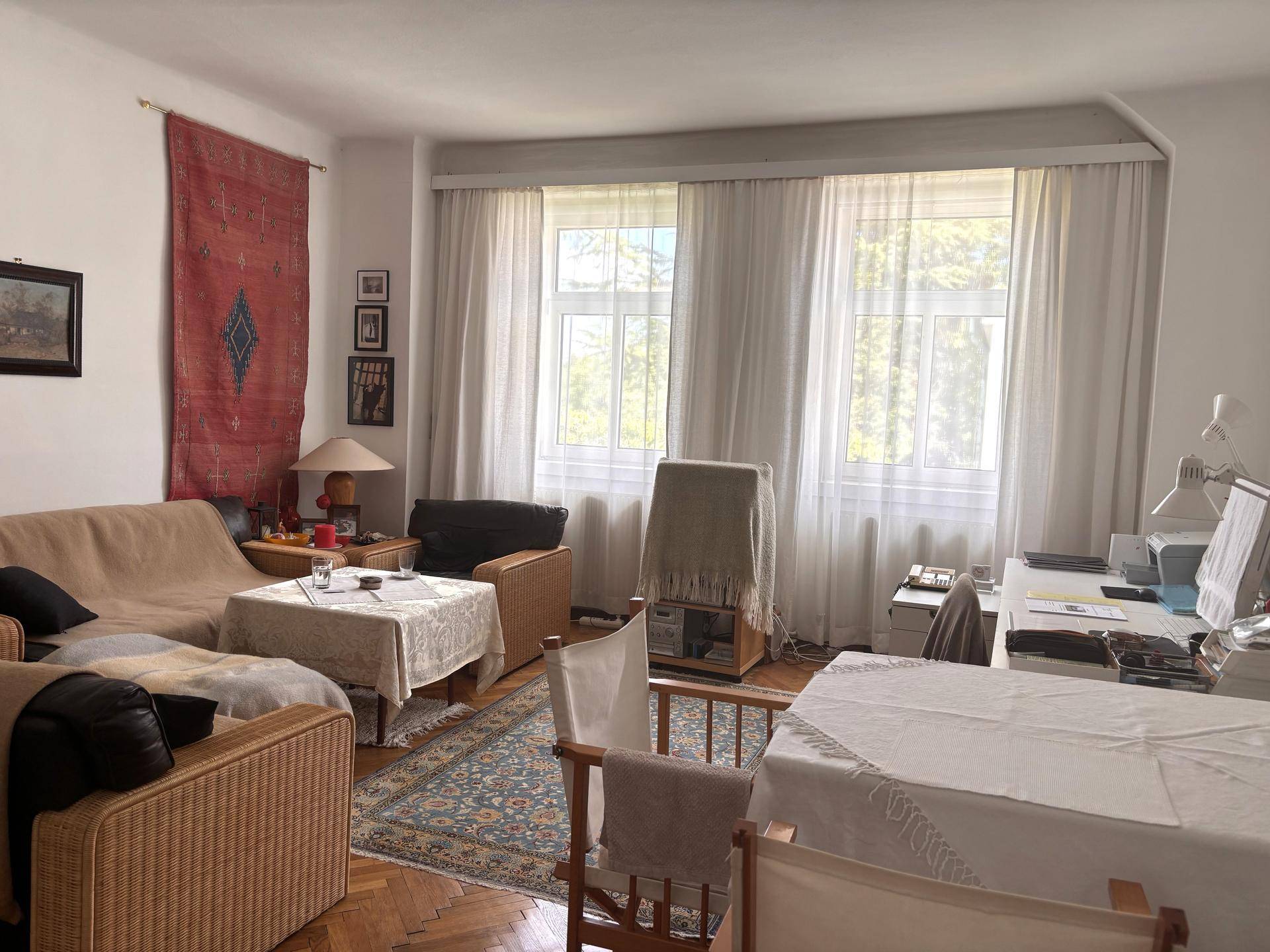 Gemütliches Wohnzimmer mit Parkettboden, großen Fenstern und traditioneller Einrichtung.