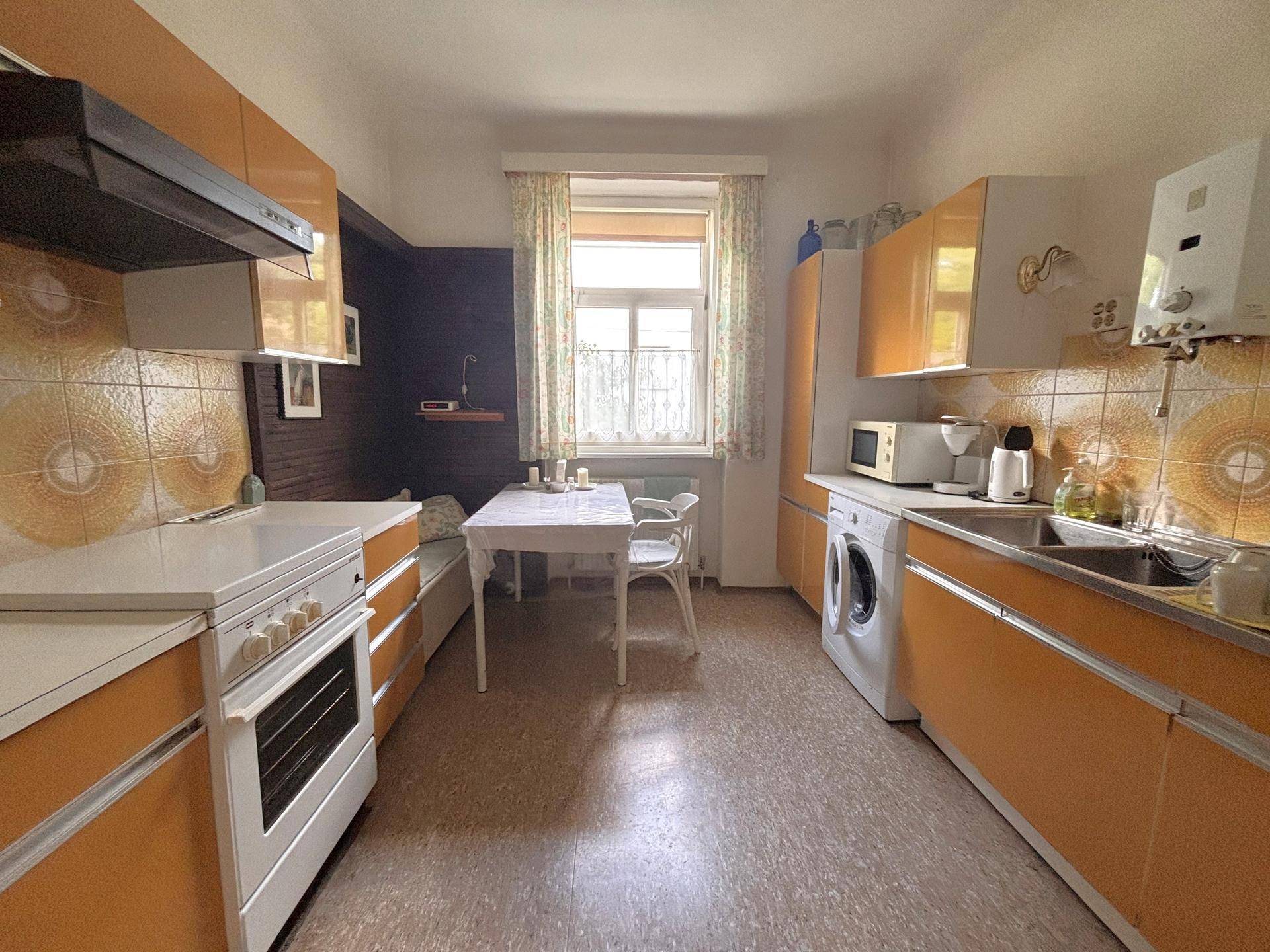 Küche im 80er-Jahre-Stil mit orangefarbenen Schränken, Essbereich und Fenster.