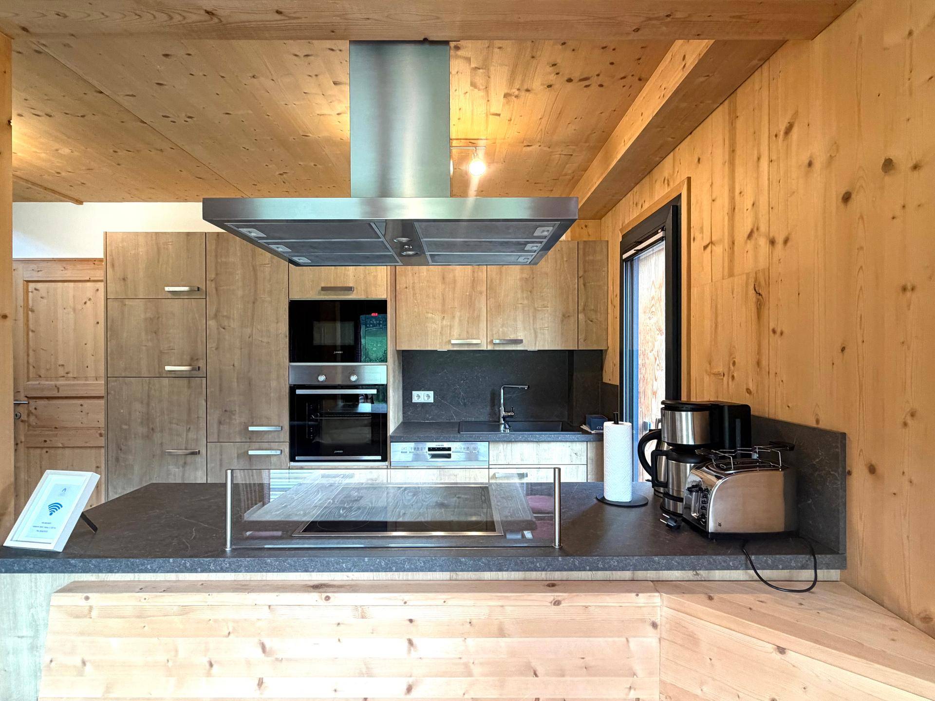 Moderne Holzküche mit integrierten Geräten, Kochinsel und Dunstabzugshaube.