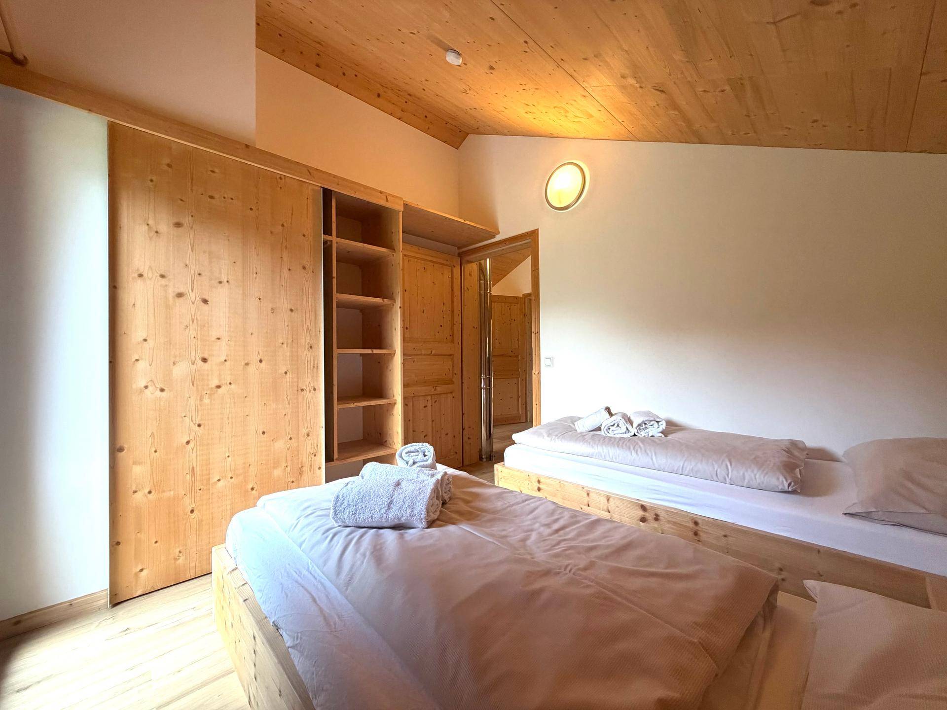 Schlafzimmer mit zwei Einzelbetten, Holzwänden und Einbauschränken.