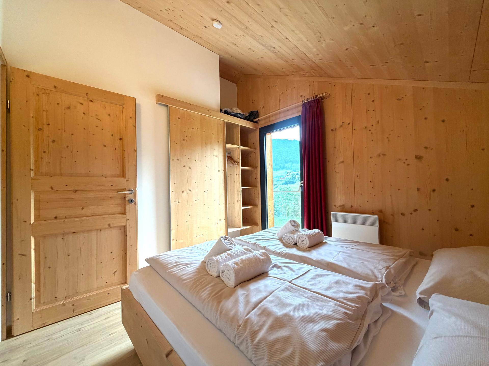Schlafzimmer mit Doppelbett, Holzwänden und integriertem Kleiderschrank.