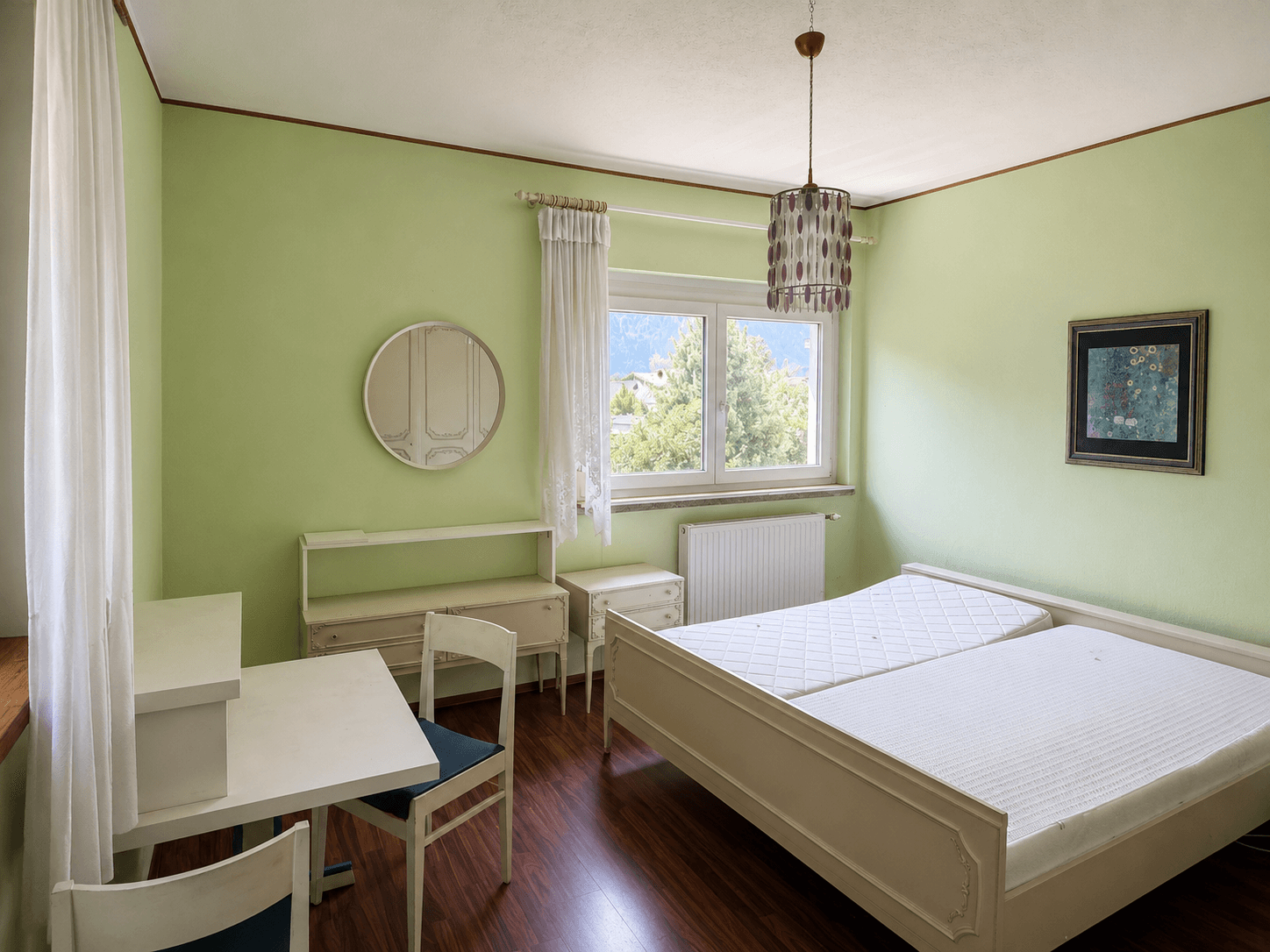 Schlafzimmer mit hellgrünen Wänden, Holzboden und Blick auf die umliegende Landschaft.
