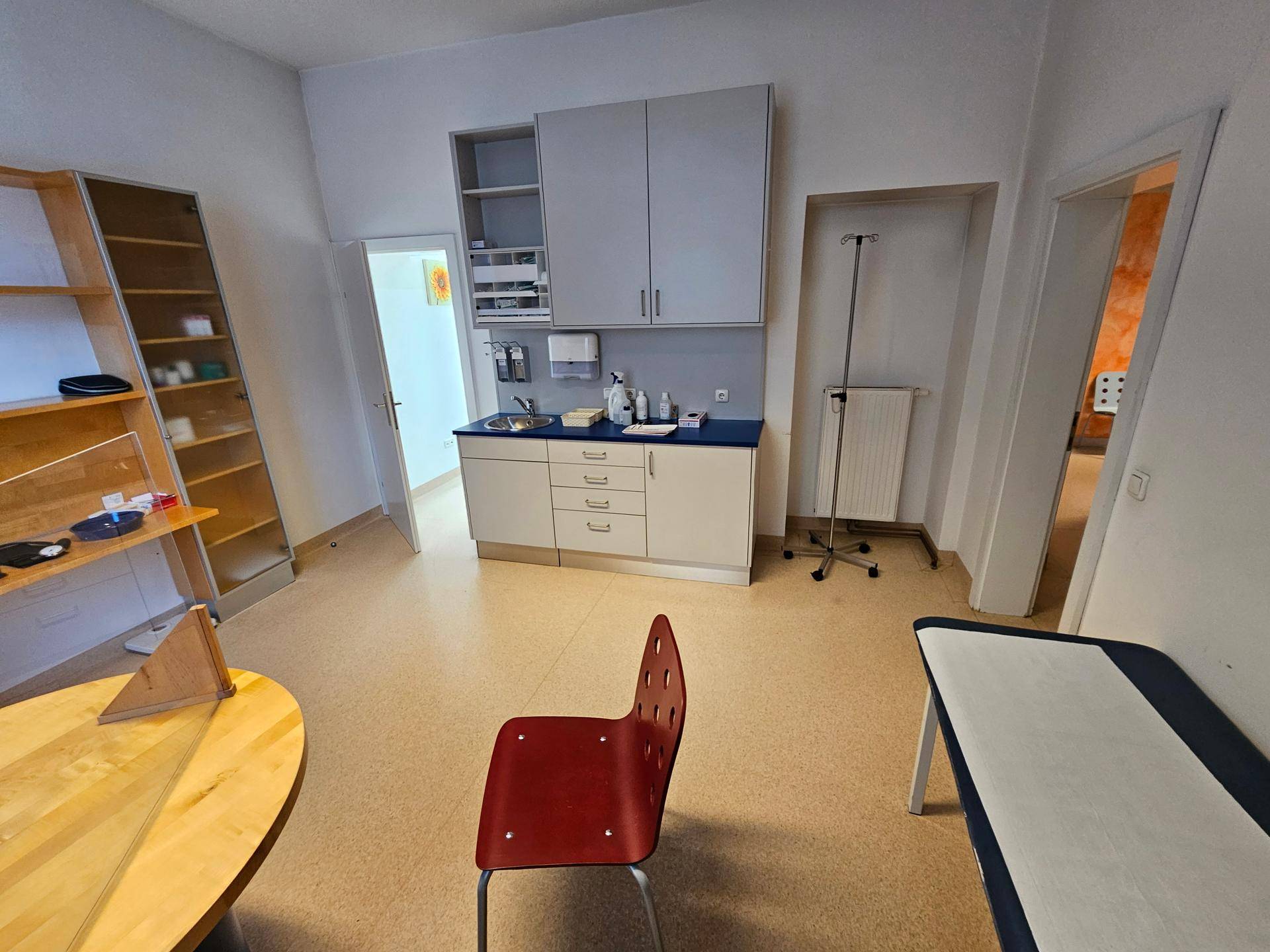 Behandlungszimmer mit Waschbecken, Schränken und medizinischer Ausstattung.