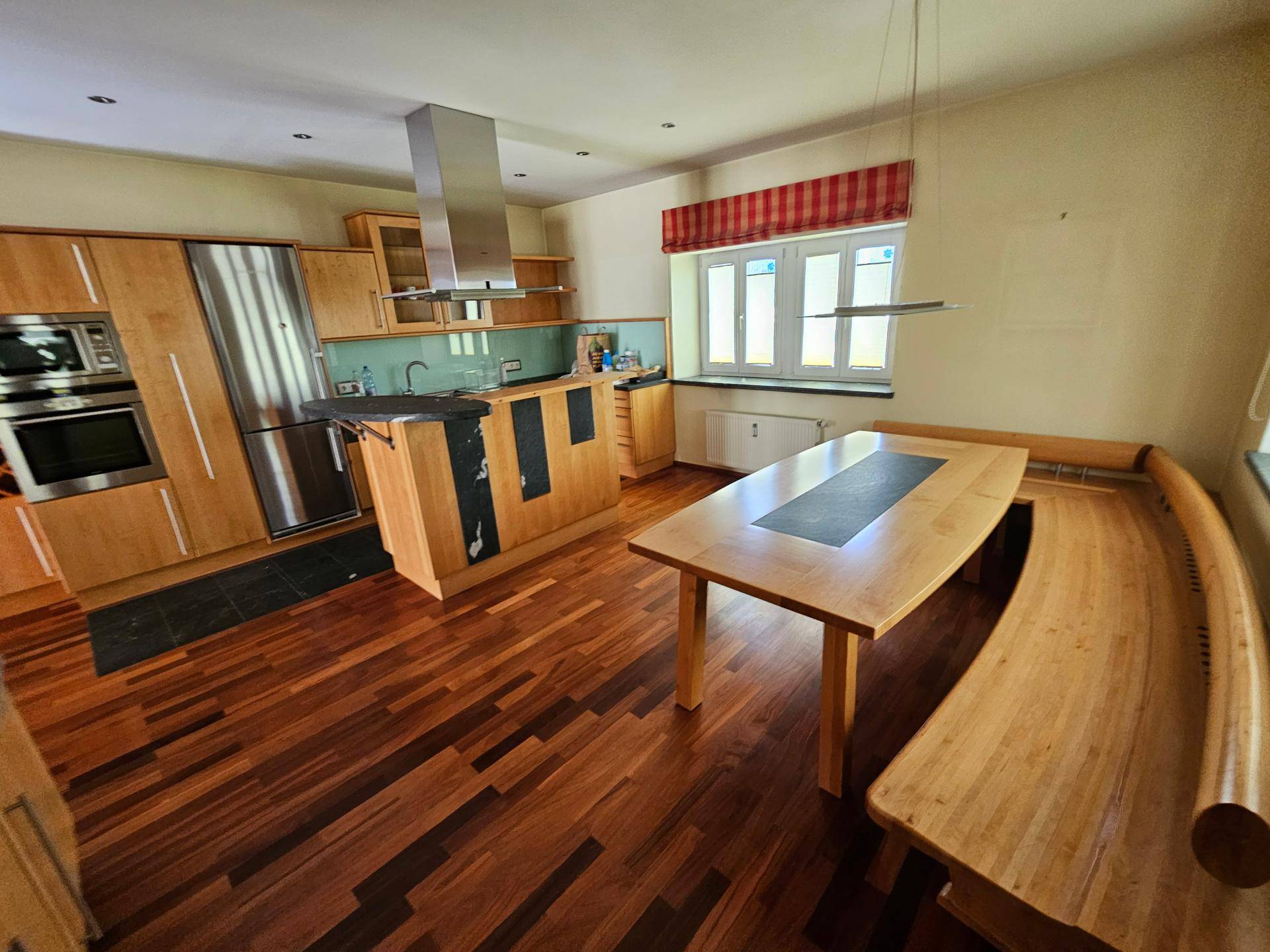 Geräumige Wohnküche mit modernen Holzschränken, Kochinsel und integriertem Essbereich.