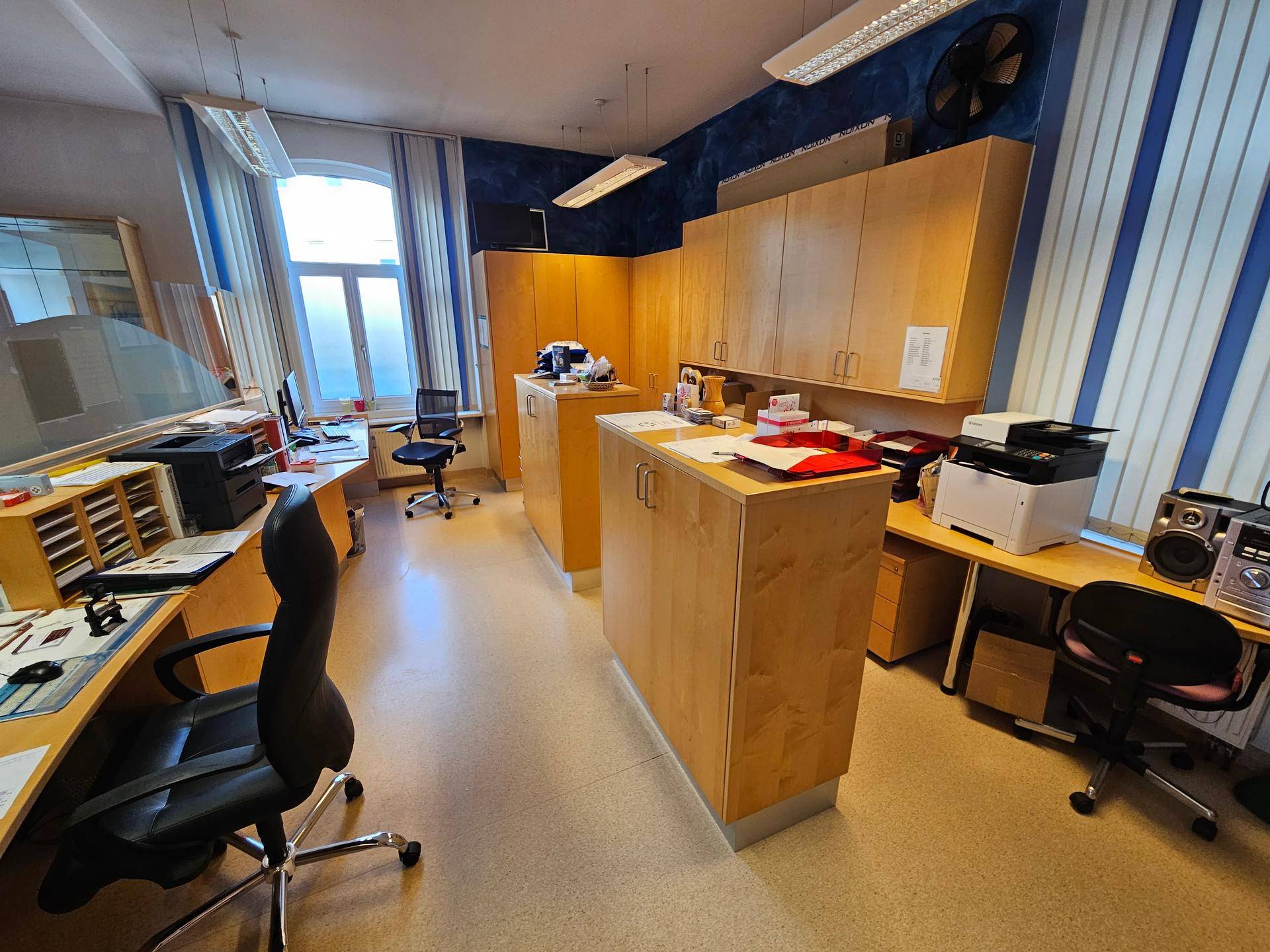 Geräumiges Büro mit mehreren Arbeitsplätzen, Holzschränken und gestreiften Wänden.