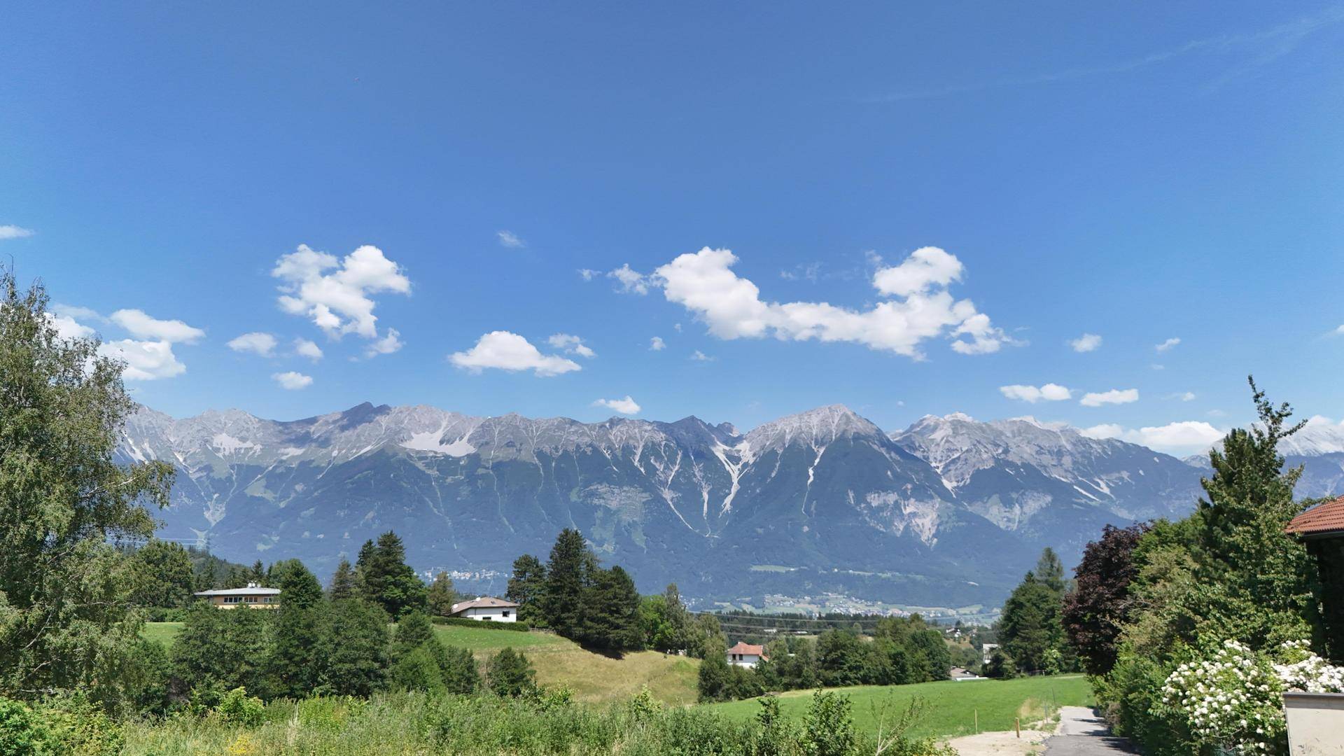 Panoramablick auf eine majestätische Bergkette mit schneebedeckten Gipfeln unter strahlend blauem Himmel.