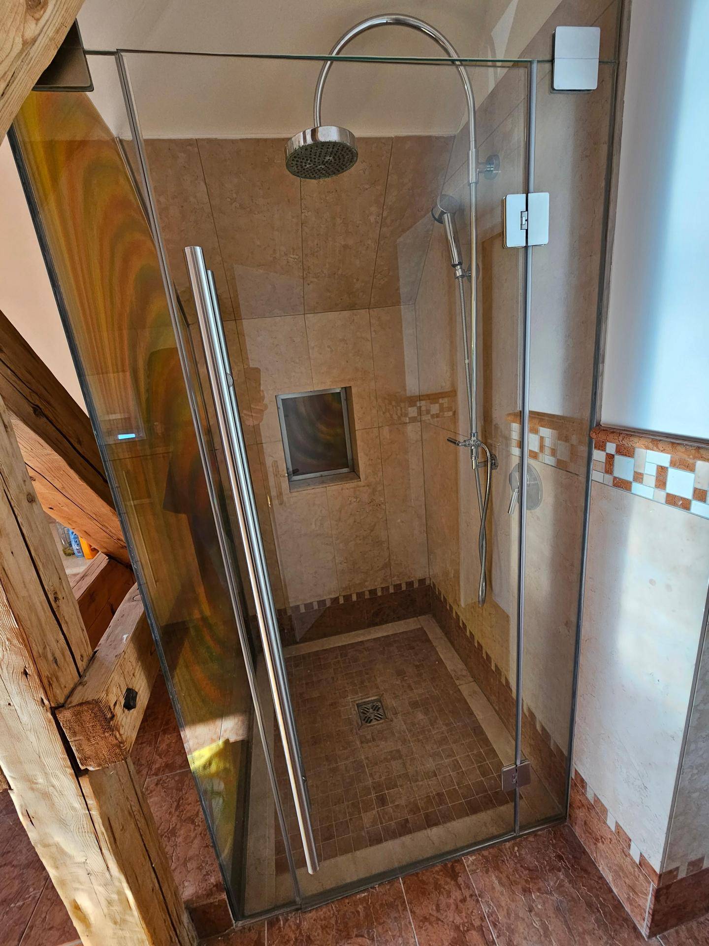 Geräumige Duschkabine mit Glaswänden und Regendusche im gefliesten Badezimmer.