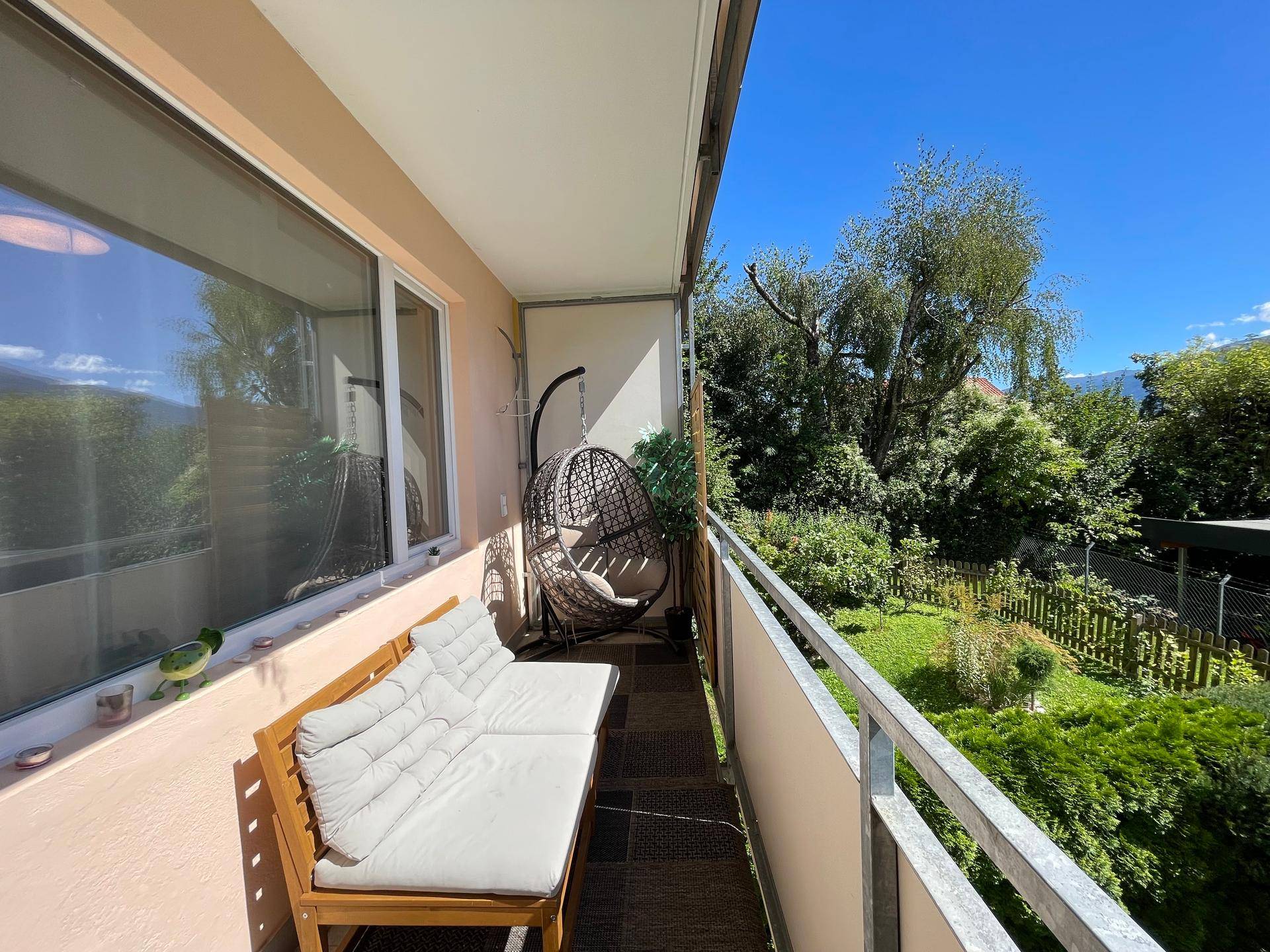 Gemütlicher Balkon mit Sitzgelegenheiten und einem schönen Blick auf den grünen Garten.