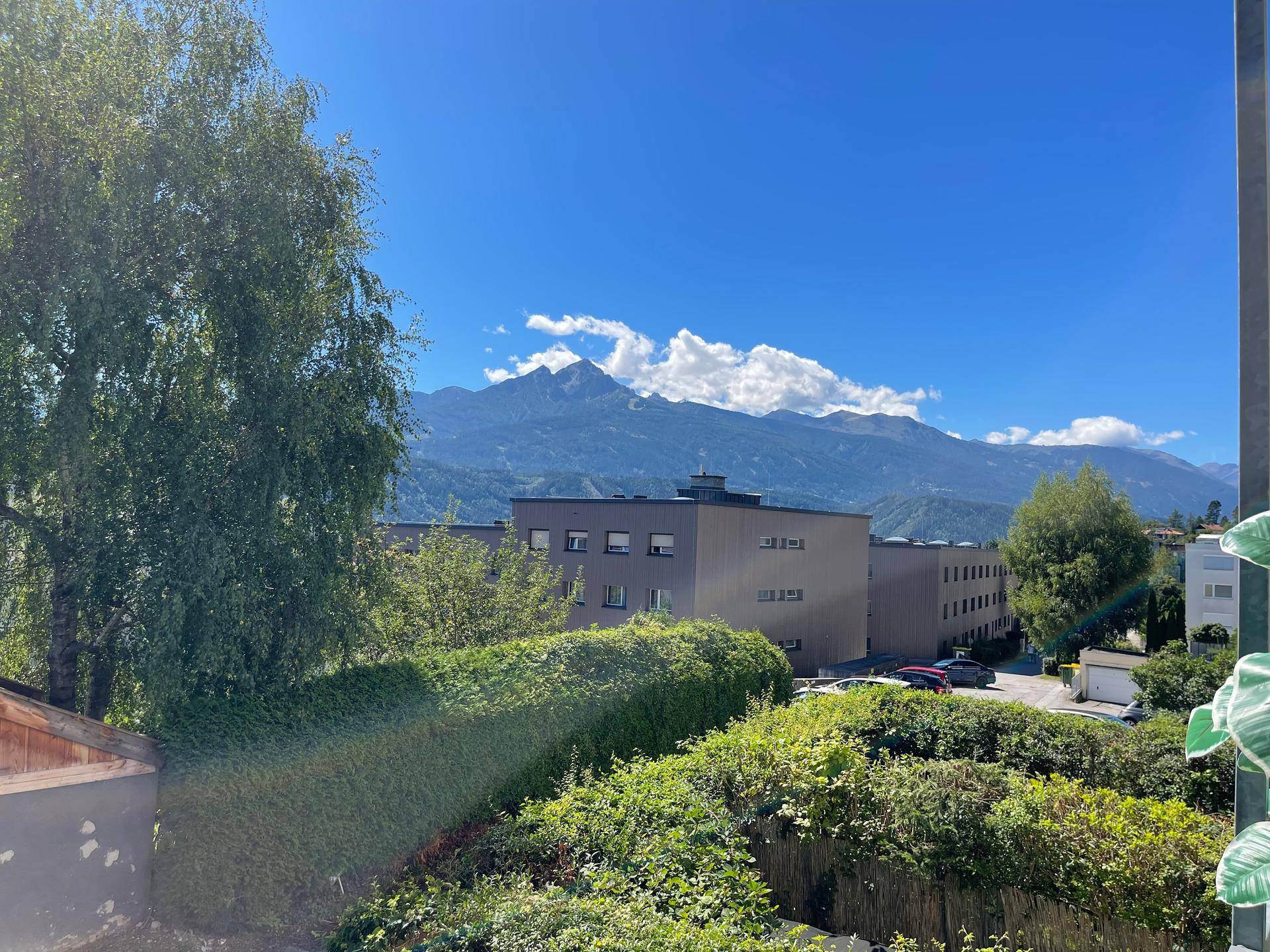 Weitblick auf die majestätischen Berge und die umliegende grüne Landschaft unter blauem Himmel.