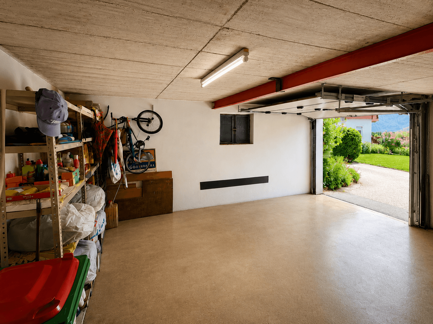 Geräumige Garage mit Regalen, Fahrradaufhängung und Zugang zum Garten.