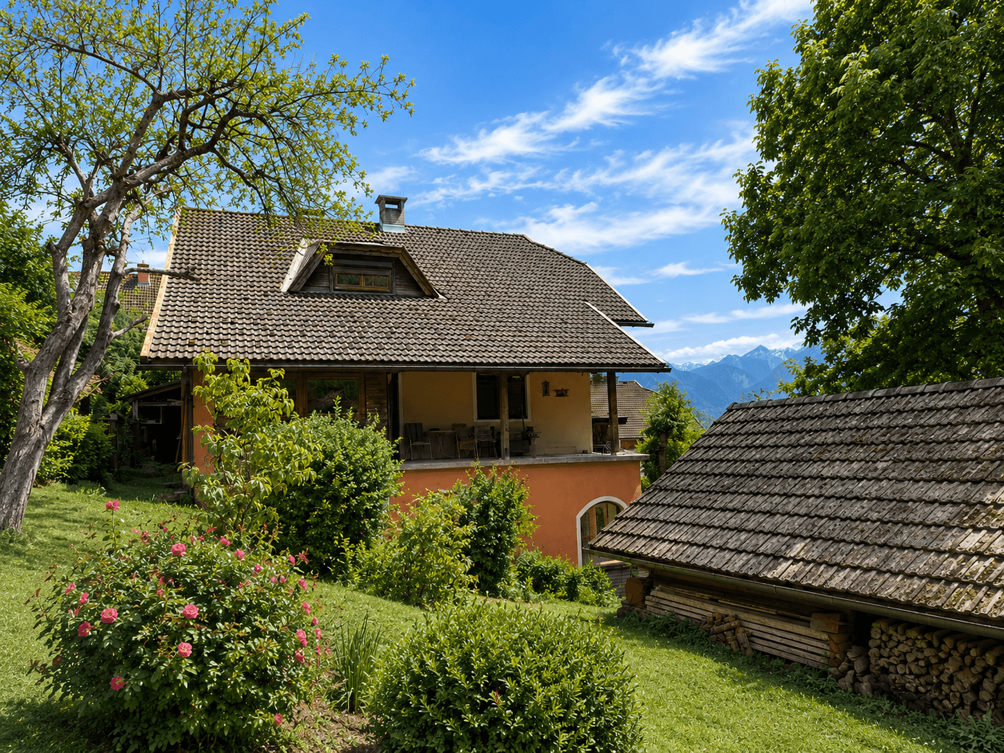 Traditionelles Haus mit Garten, Holzschuppen und Bergblick im Hintergrund.