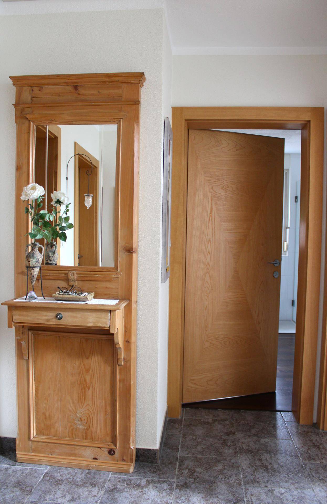 Heller Flur mit Holztür, Spiegelgarderobe und Fliesenboden.