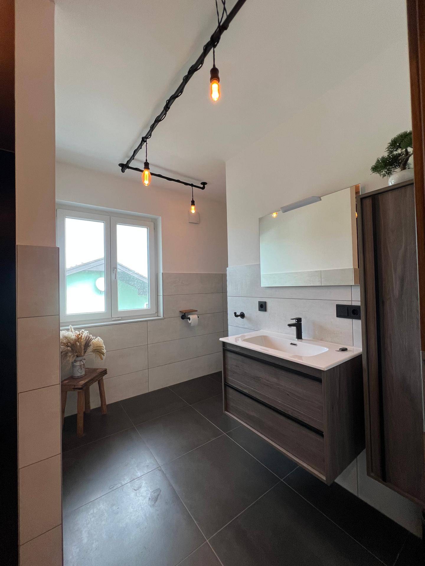 Modernes Badezimmer mit Waschtisch, Spiegelschrank und Fenster für Tageslicht.