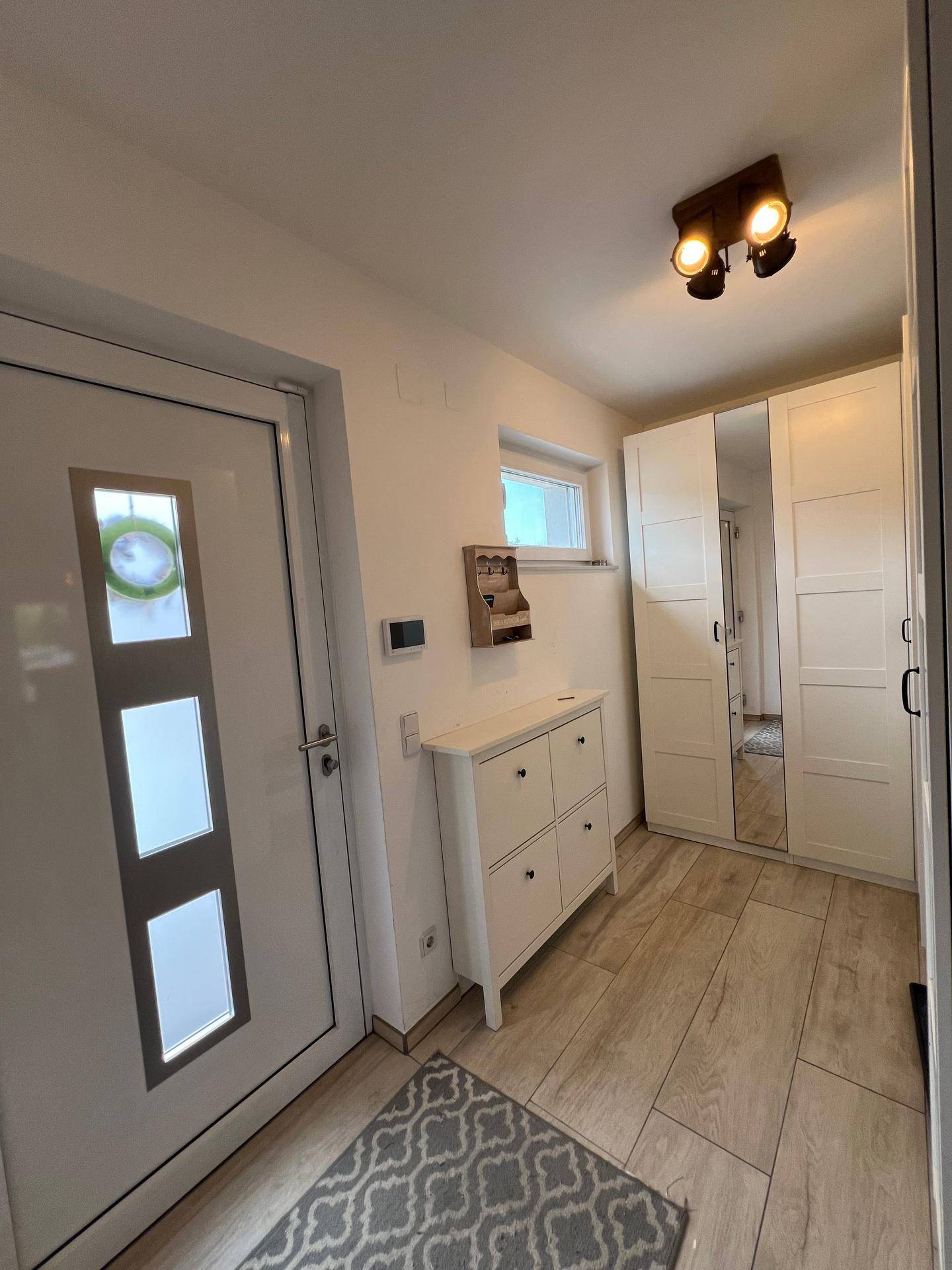 Heller Eingangsbereich mit weißer Haustür, Schuhschrank und praktischen Spiegelschränken.