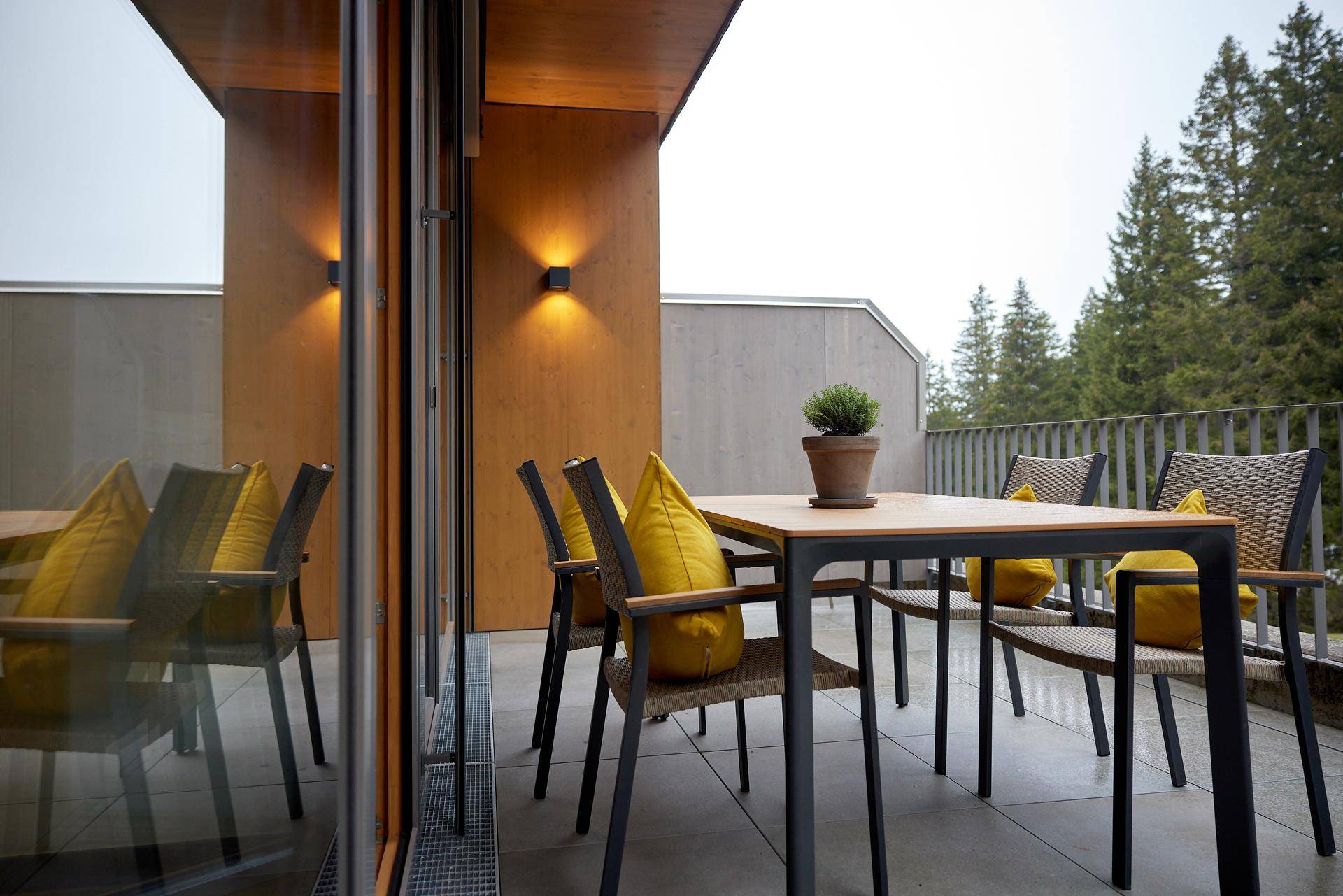 Geräumige Terrasse mit Esstisch und Stühlen, ideal für Mahlzeiten im Freien mit Waldblick.