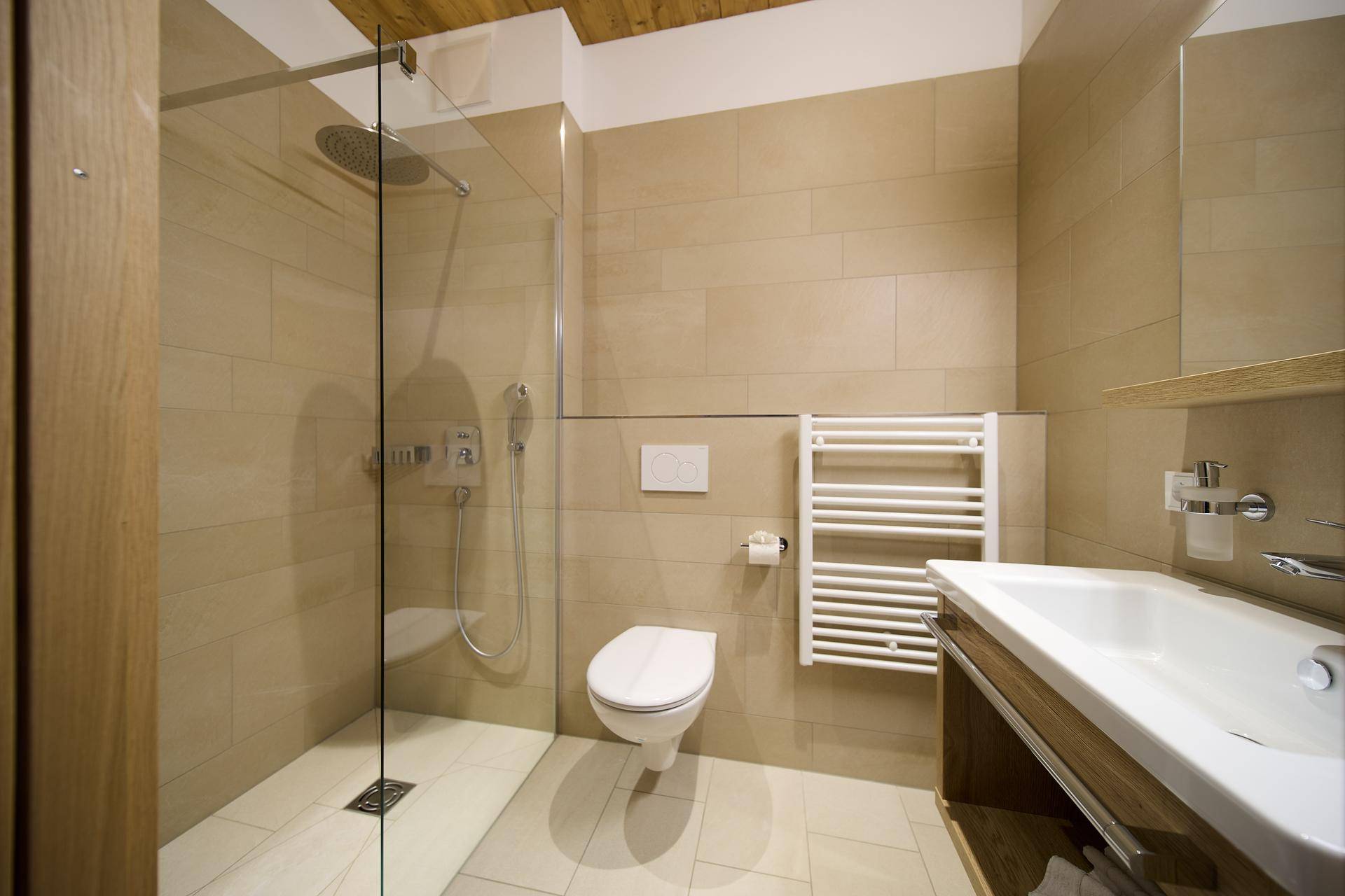 Modernes Badezimmer mit begehbarer Dusche, Wand-WC, Waschbecken und beheiztem Handtuchhalter.