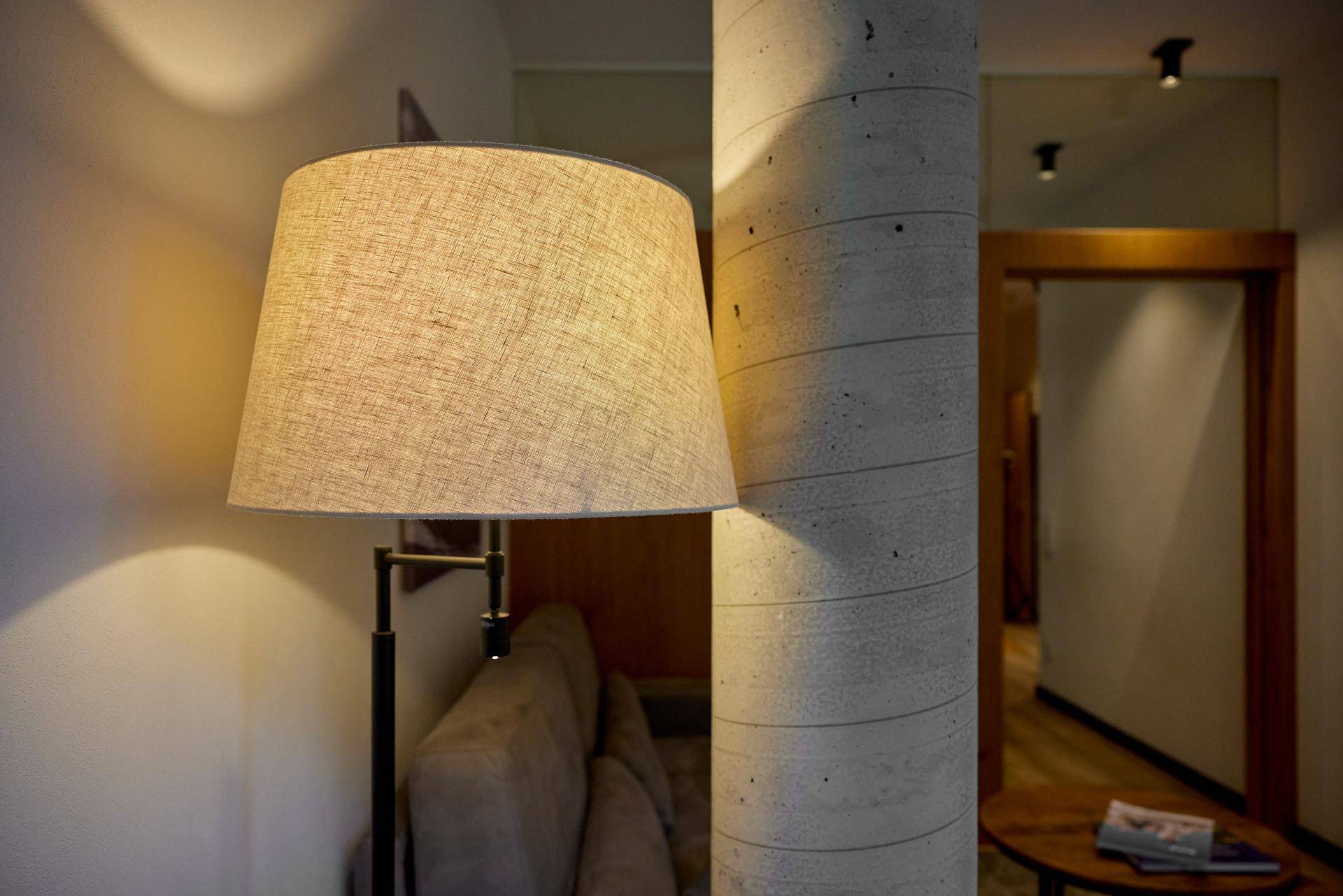 Stehlampe neben einer modernen Betonsäule im Wohnbereich, die für gemütliches Licht sorgt.