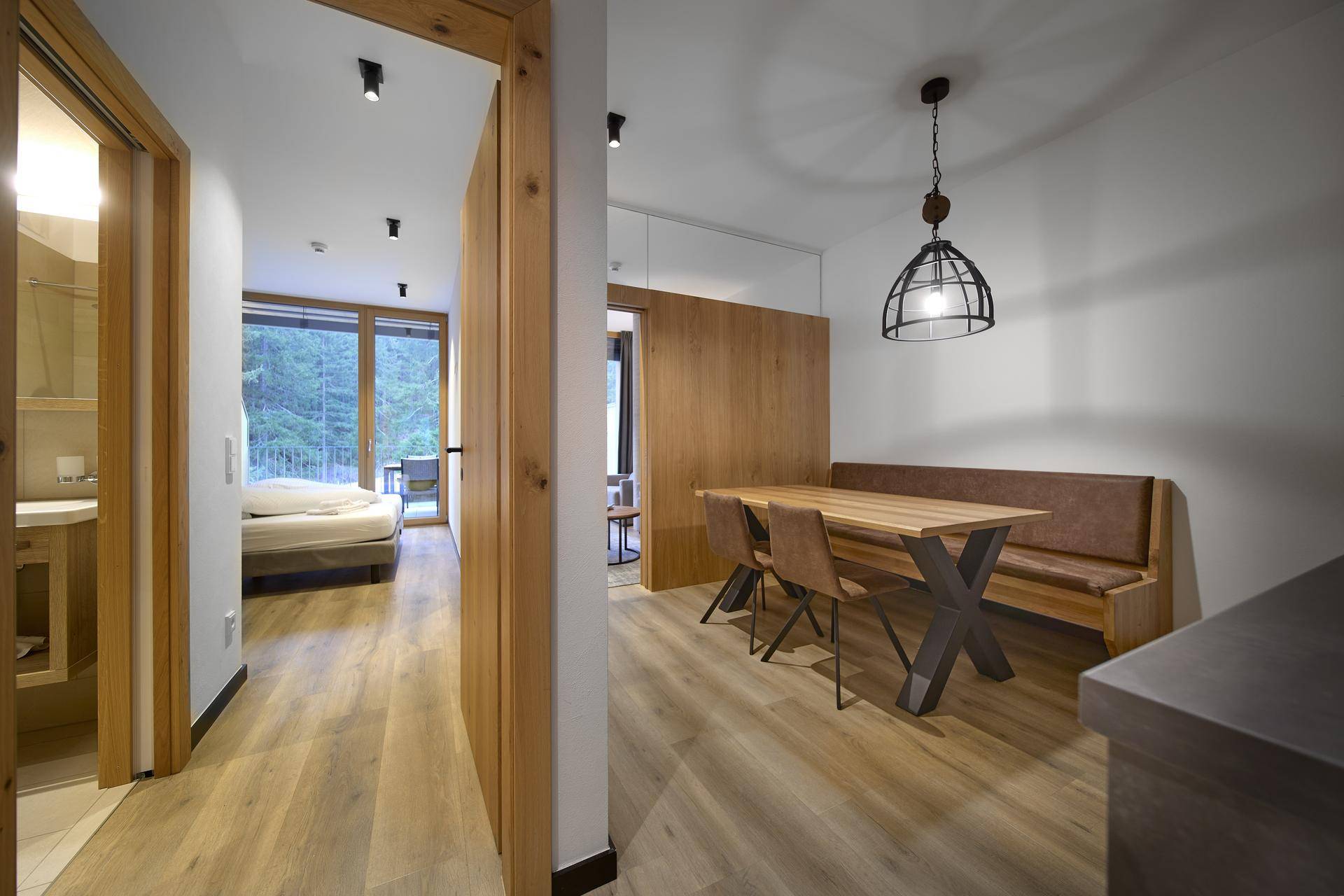 Heller Flur mit Holzboden, der zu Schlafzimmer und Bad führt, mit Blick auf den Essbereich.