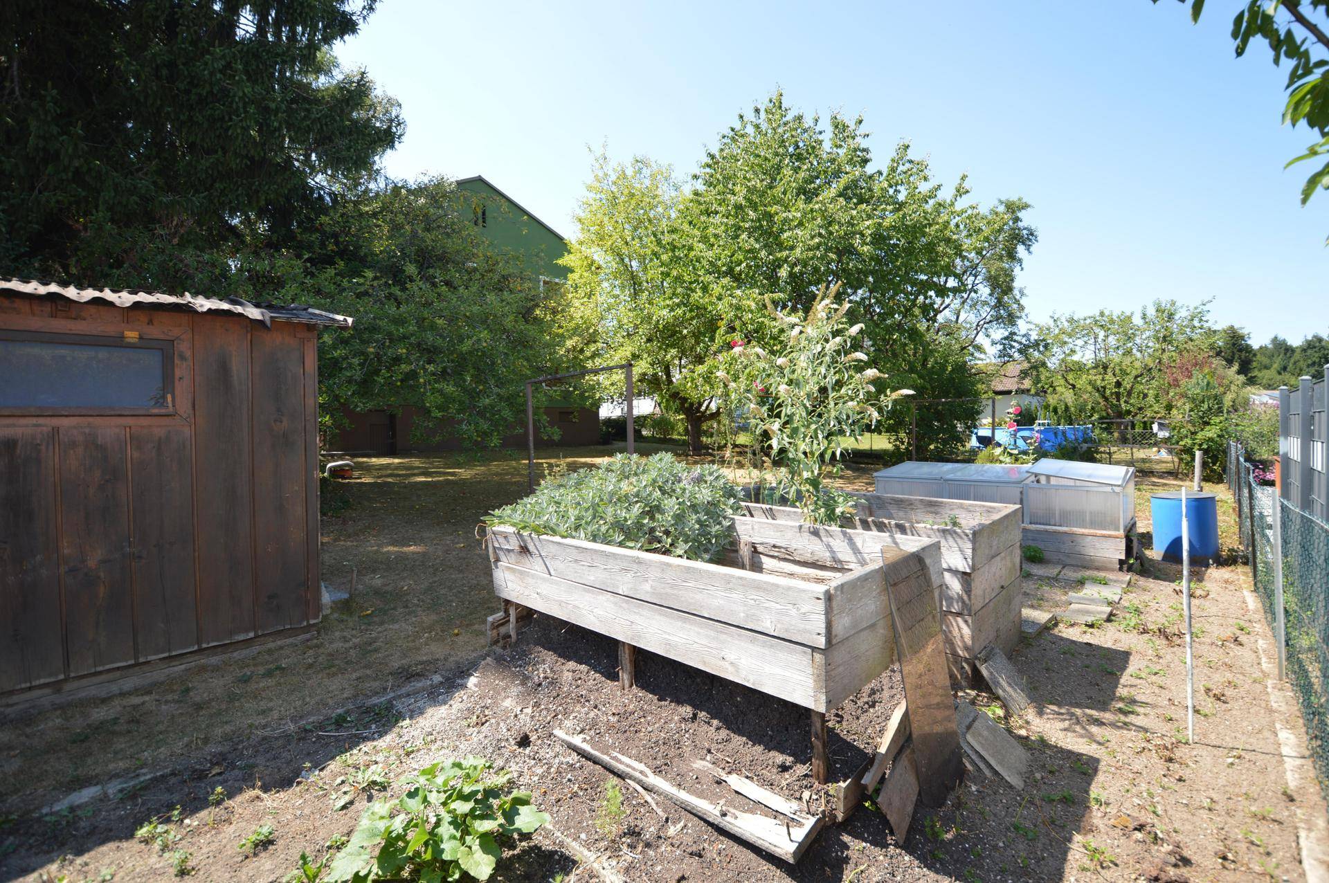 Nutzgartenbereich mit Hochbeeten, einem kleinen Holzschuppen und weiteren Anbauflächen.