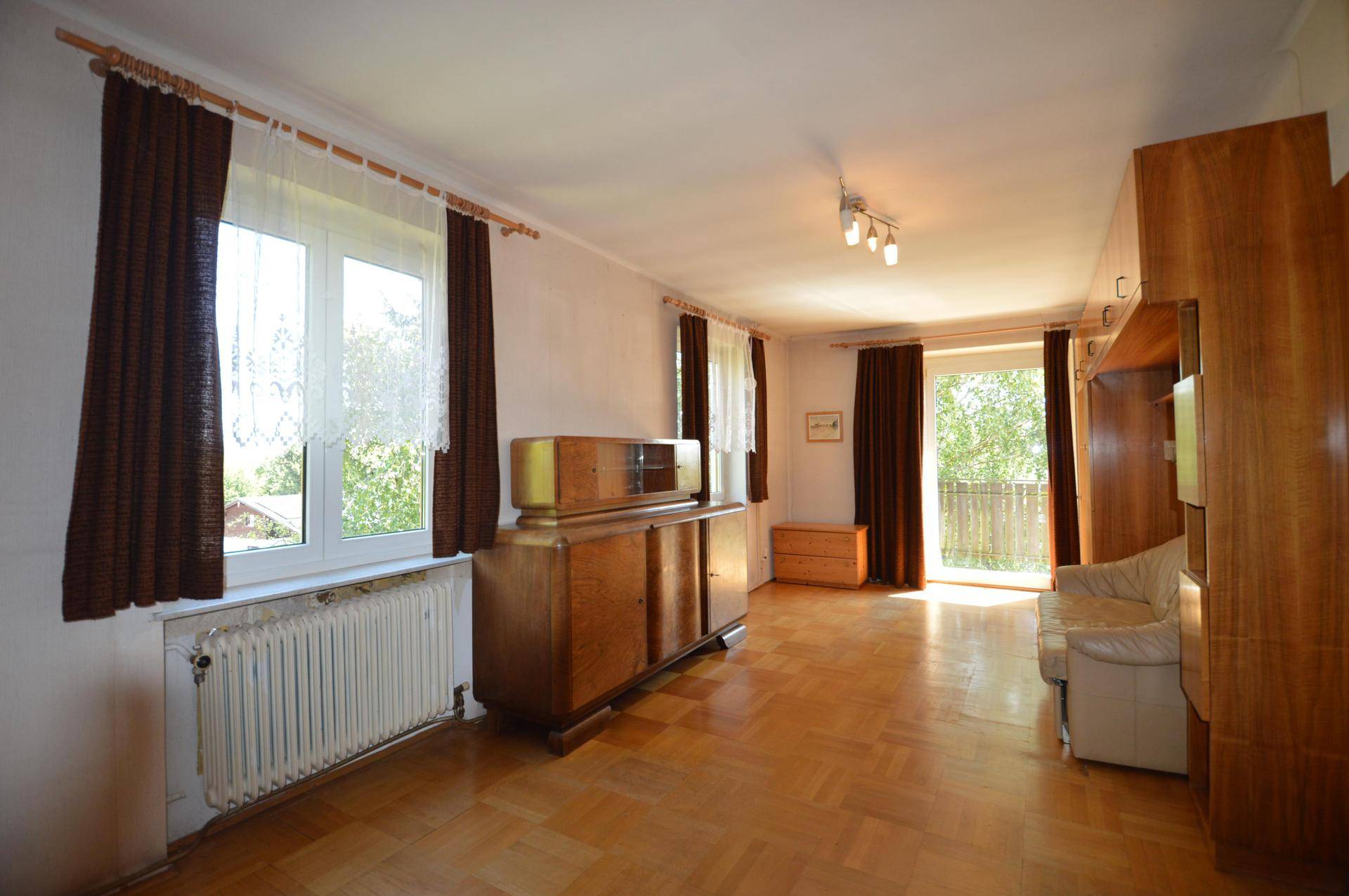 Geräumiges Wohnzimmer mit Parkettboden, Einbauschränken und direktem Zugang zu einem Balkon.