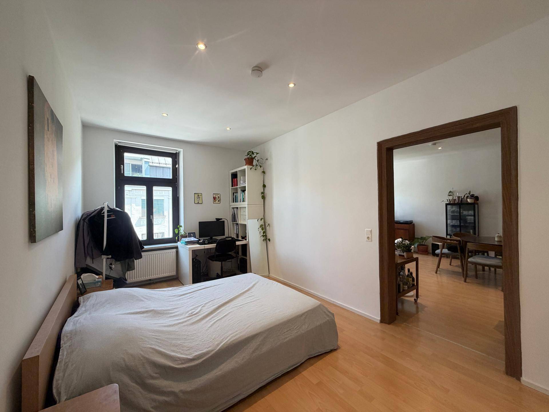 Gemütliches Schlafzimmer mit Arbeitsbereich am Fenster und direktem Zugang zum Wohnbereich.