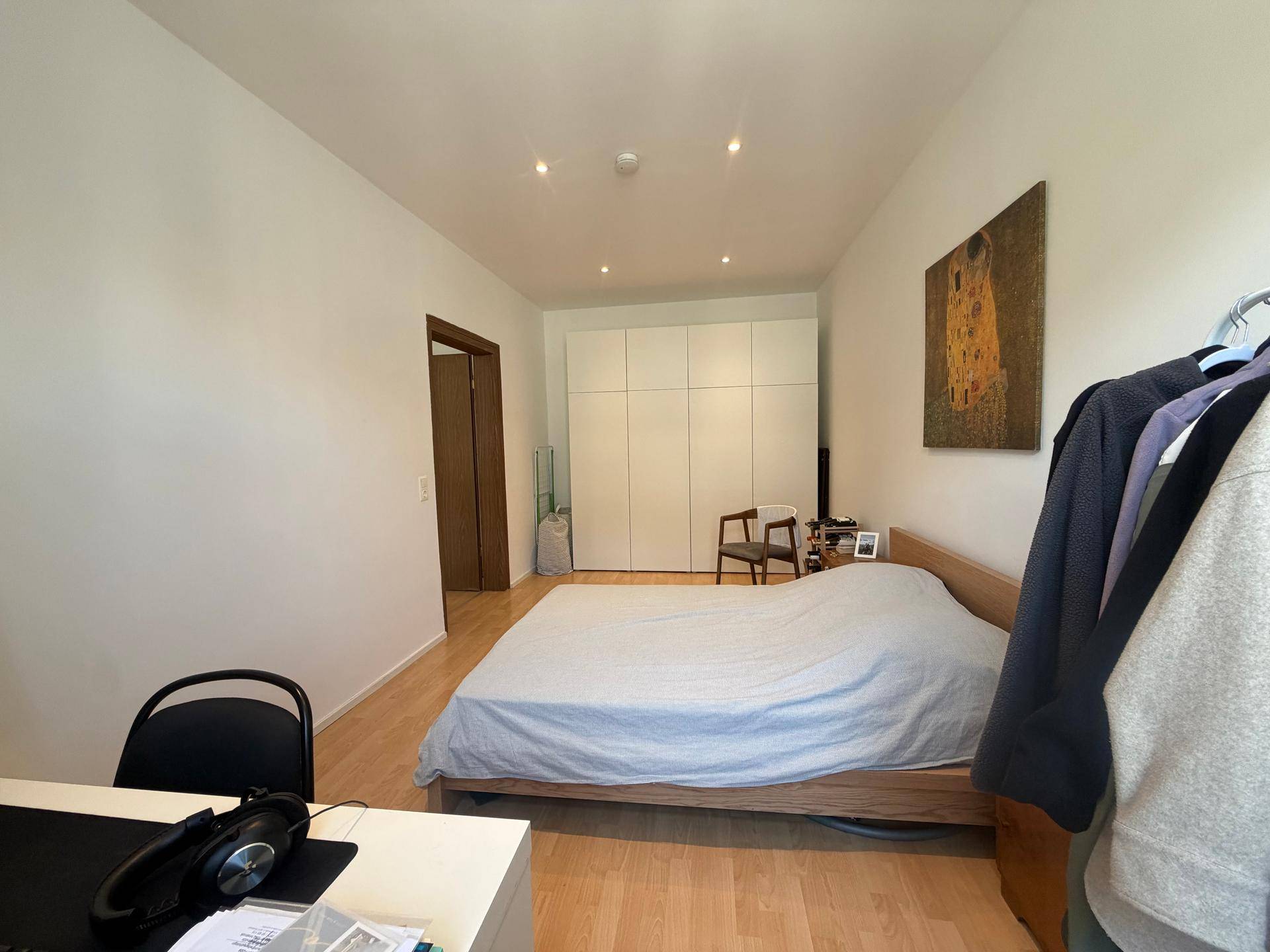 Schlafzimmer mit großem Bett, Einbauschränken und hellem Holzboden, bietet viel Stauraum.