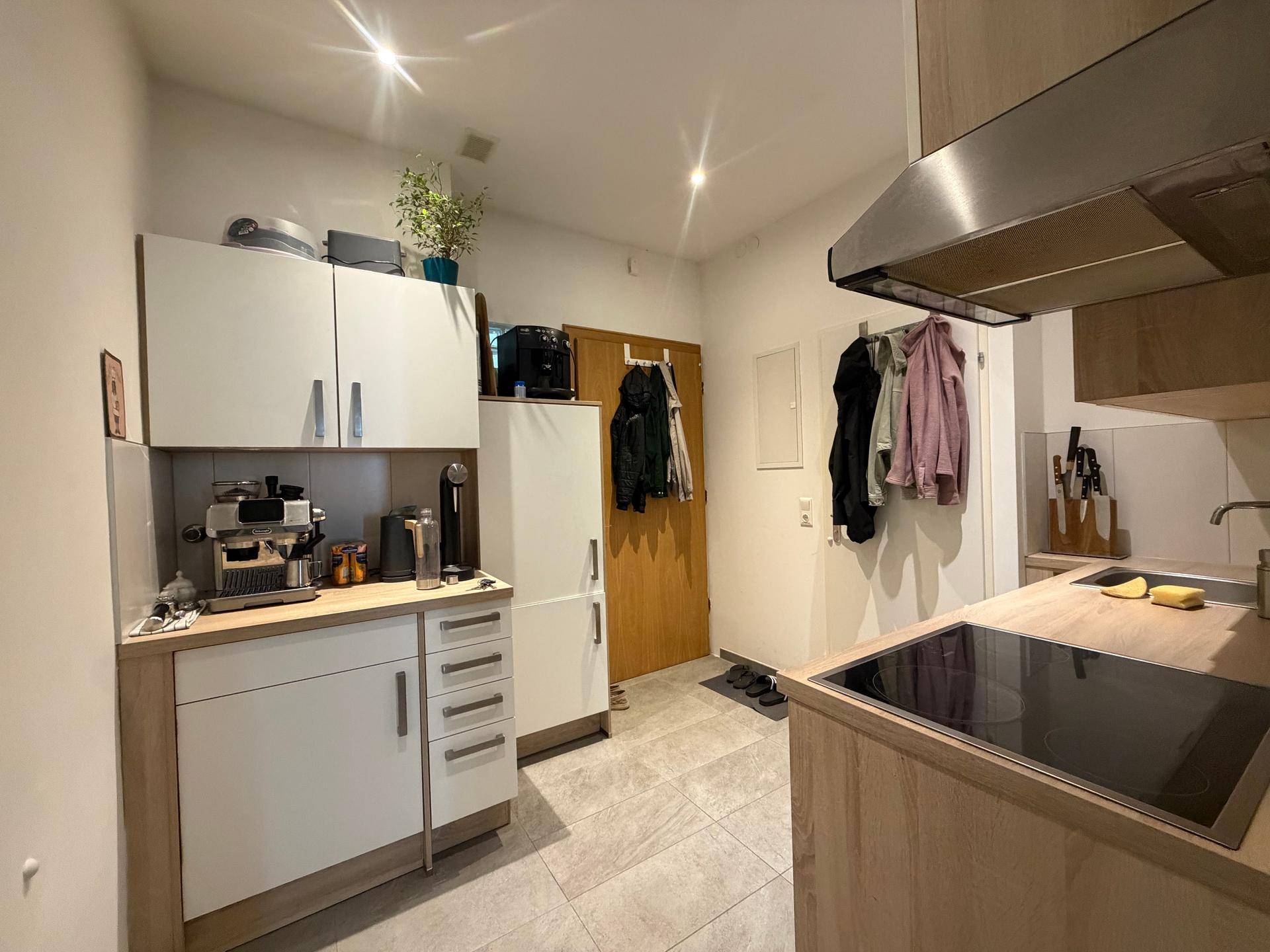 Funktionale Küche mit Induktionskochfeld, Kühlschrank und viel Stauraum für Küchenutensilien.