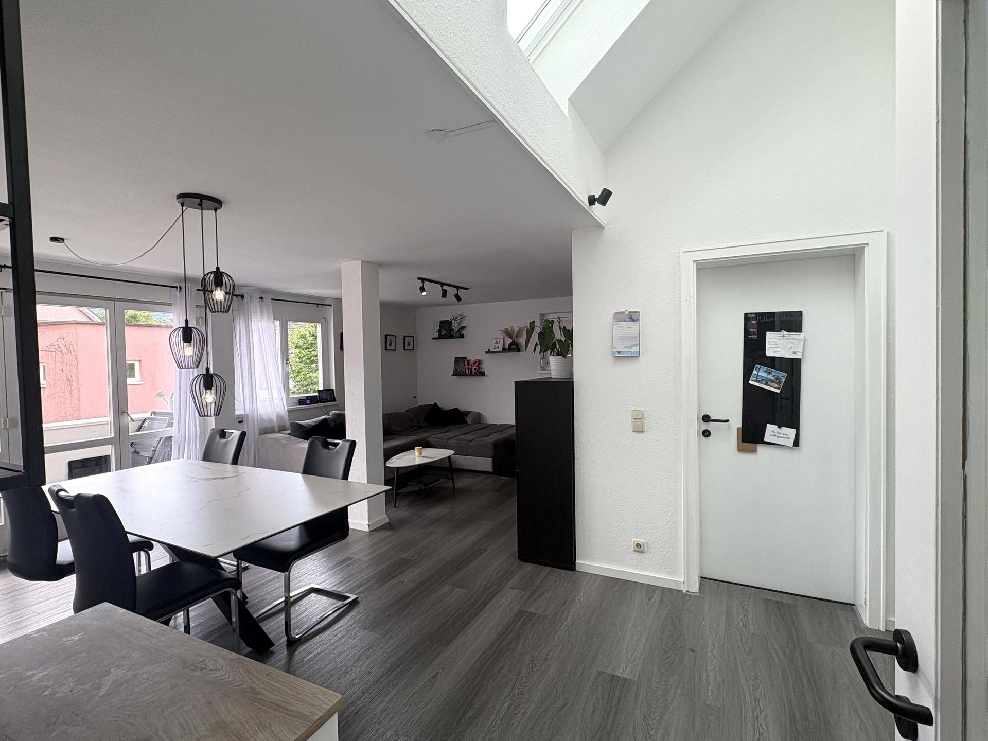 Heller offener Wohn- und Essbereich mit Dachfenstern, modernem Design und Laminatboden.