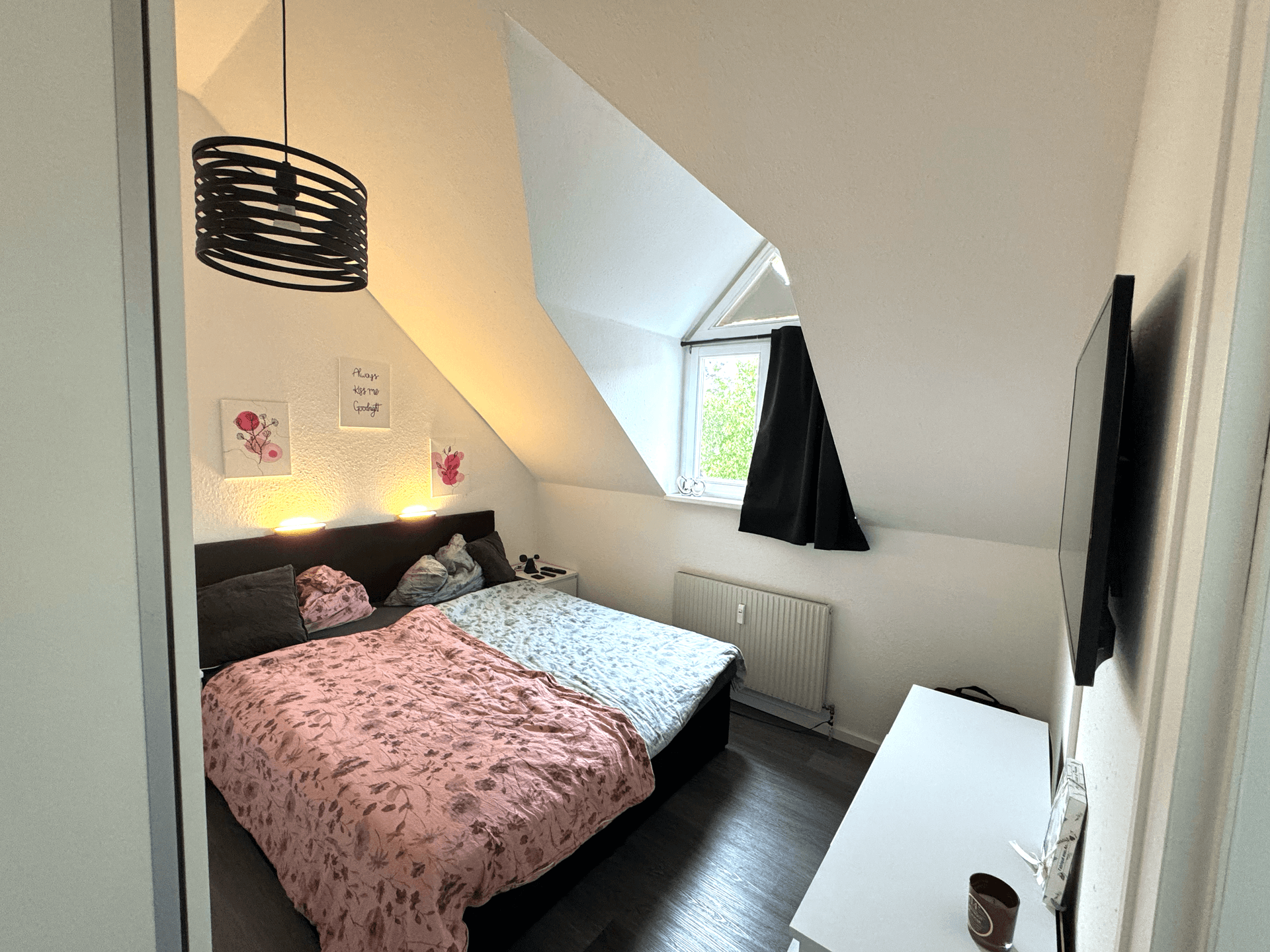 Schlafzimmer im Dachgeschoss mit schrägen Wänden, Doppelbett und Dachfenster für natürliches Licht.