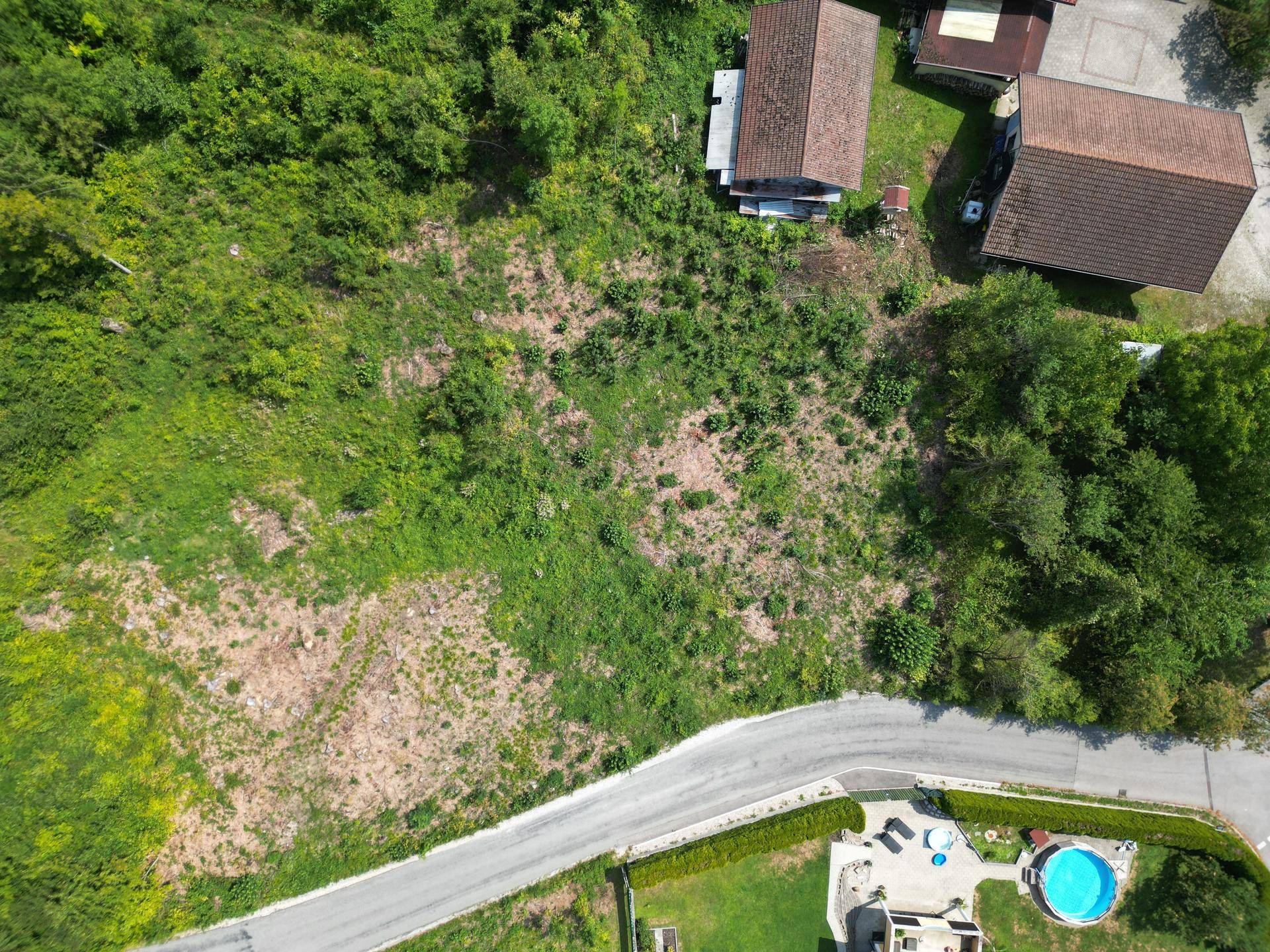 Luftaufnahme eines großen, grünen Grundstücks mit angrenzender Straße und Häusern.