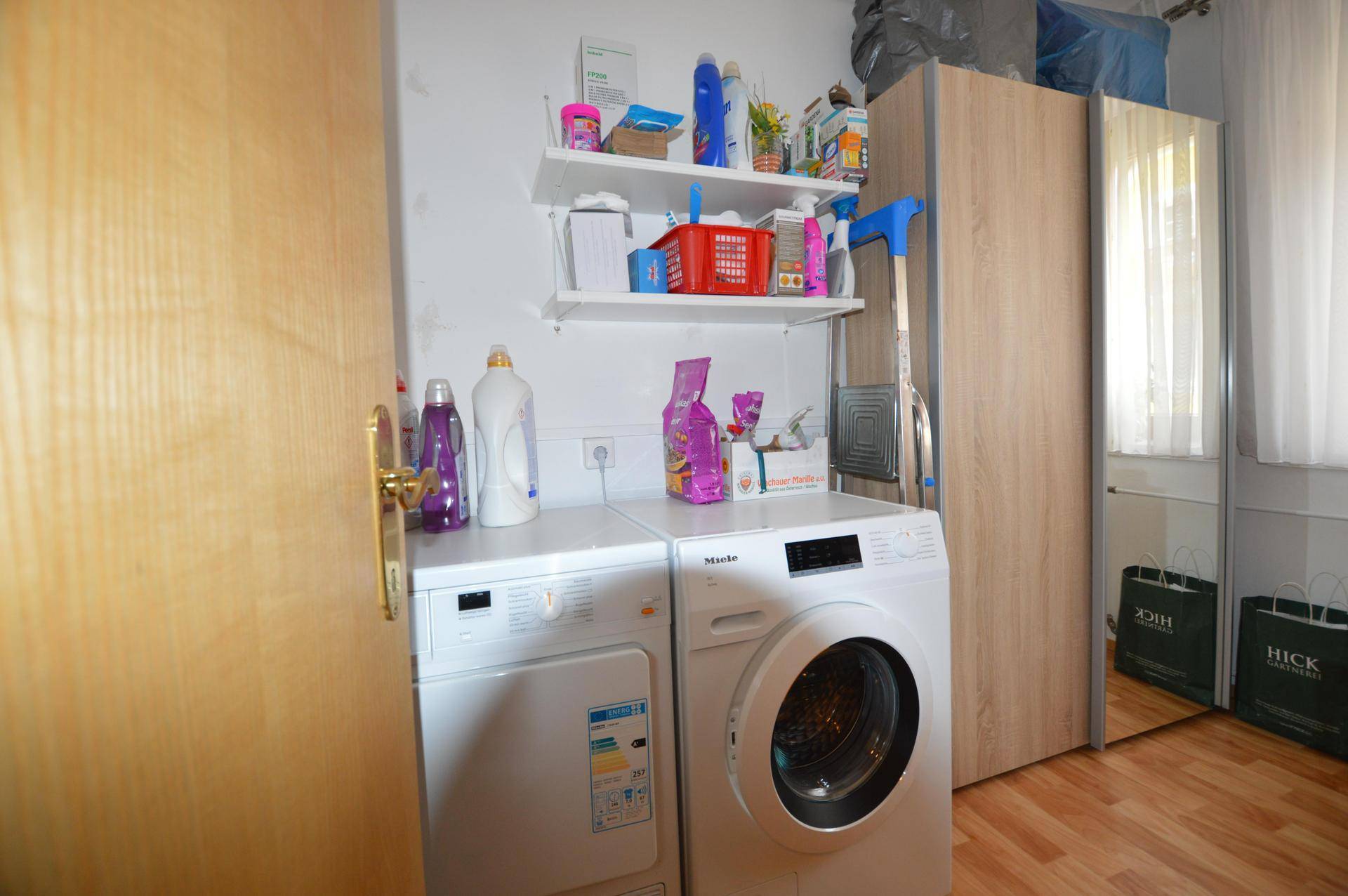 Praktischer Hauswirtschaftsraum mit Waschmaschine, Trockner und Regalen für Vorräte.