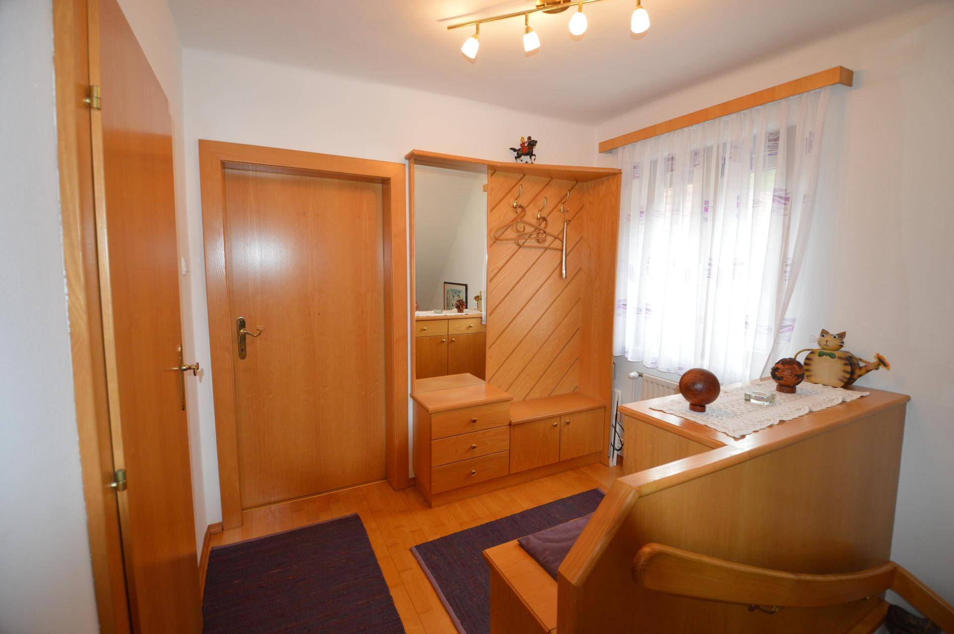 Eingangsbereich mit Holzgarderobe, Spiegel und hellem Laminatboden.
