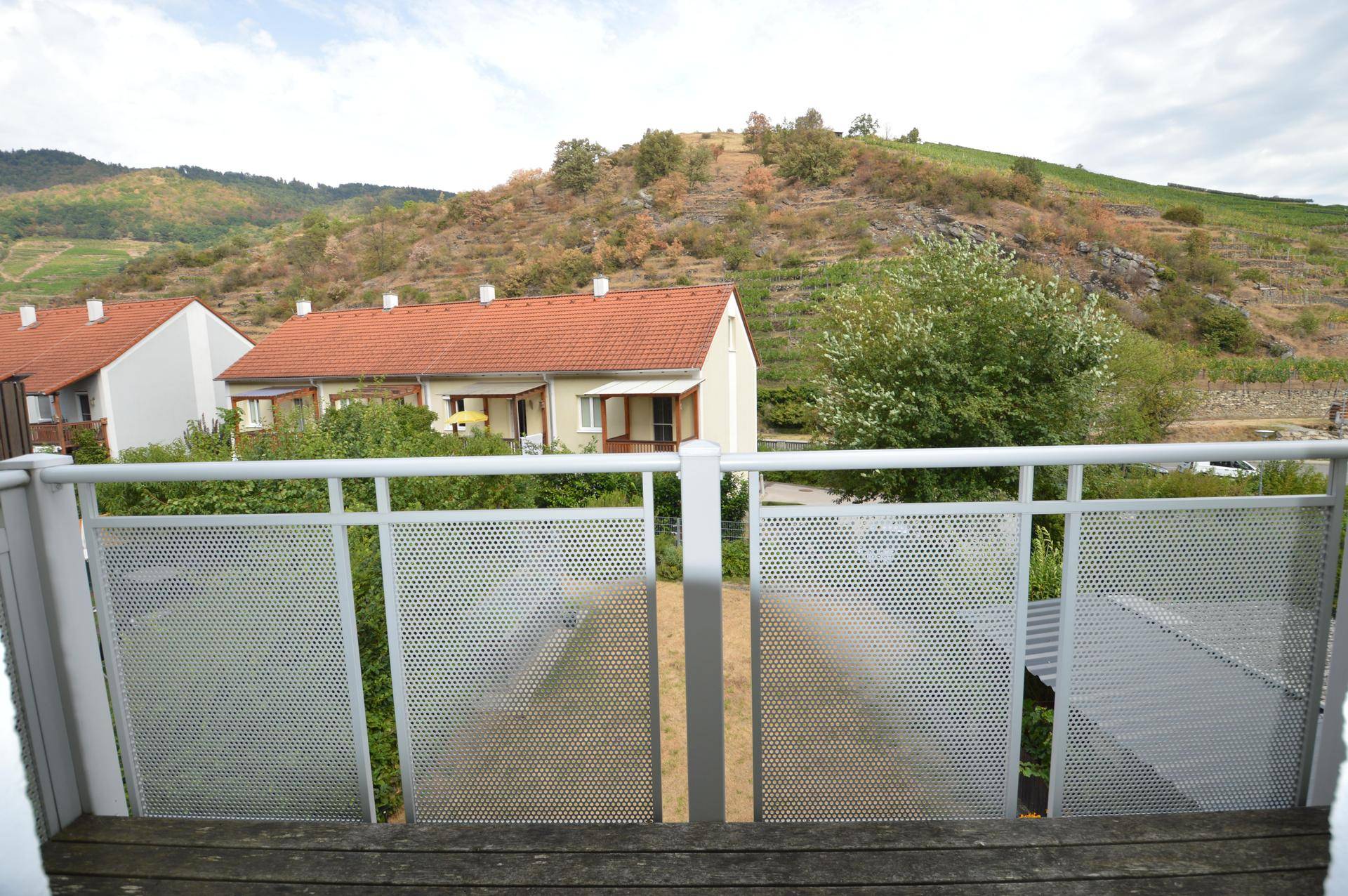 Ausblick vom Balkon auf benachbarte Häuser und die umliegenden Weinberge.