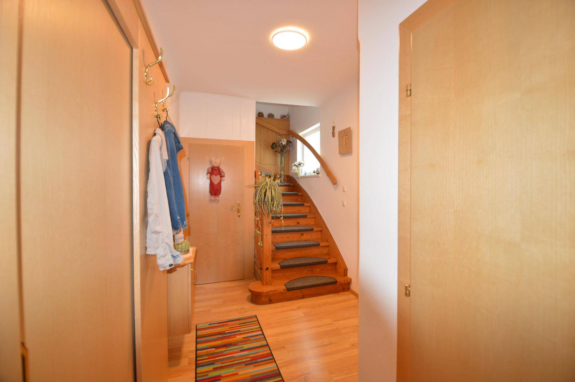 Heller Flur mit Holztreppe, die in die oberen Stockwerke führt.