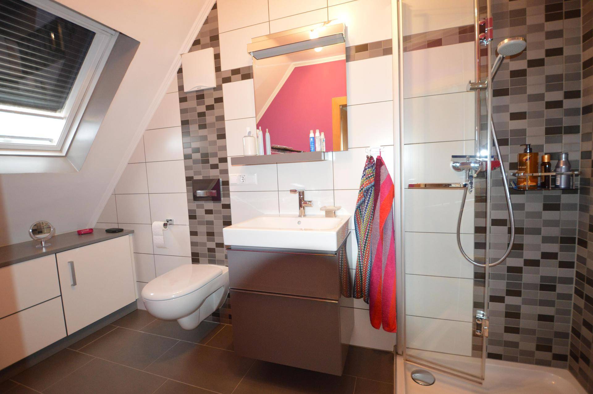 Modernes Badezimmer im Dachgeschoss mit Dachfenster, Dusche und farbiger Akzentwand.
