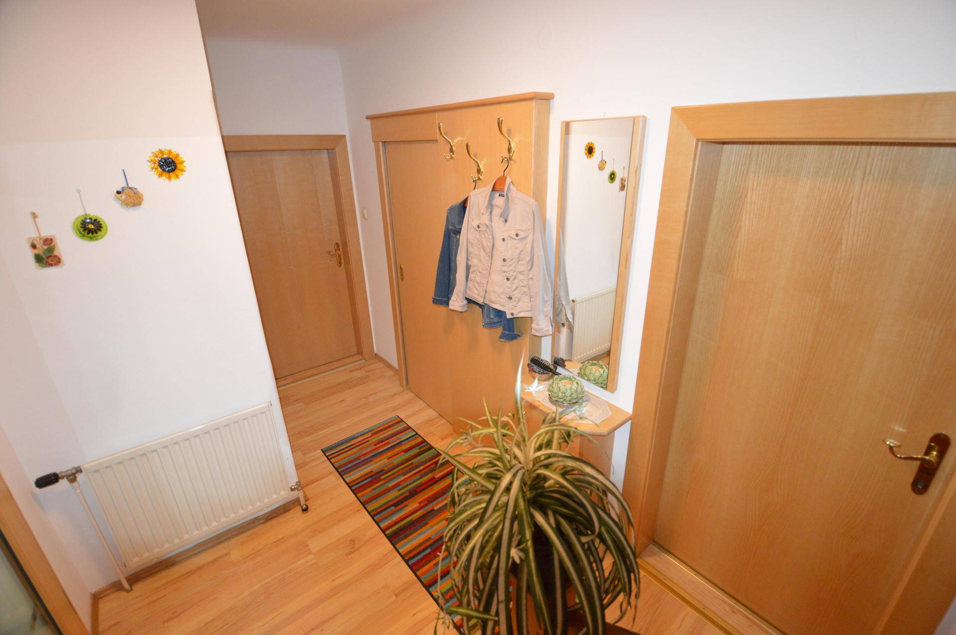 Heller Flur mit Holzboden, Garderobe und Spiegel.