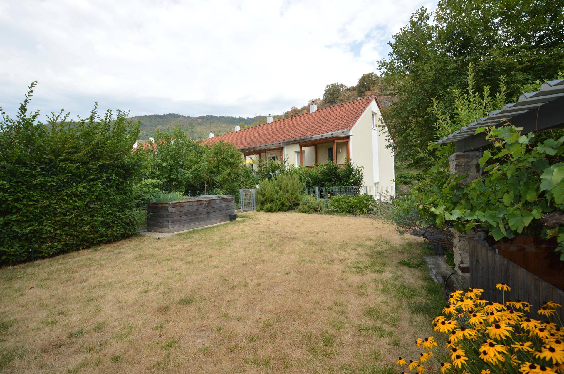 Garten mit Hochbeet und Blick auf benachbarte Häuser und die umliegende Natur.