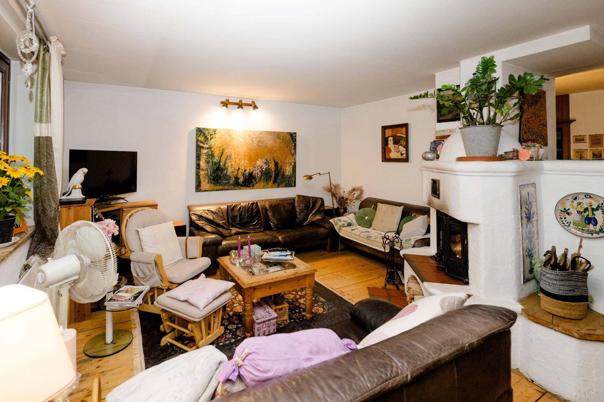 Gemütliches Wohnzimmer mit bequemen Sofas, Holzboden und einem traditionellen Kachelofen.
