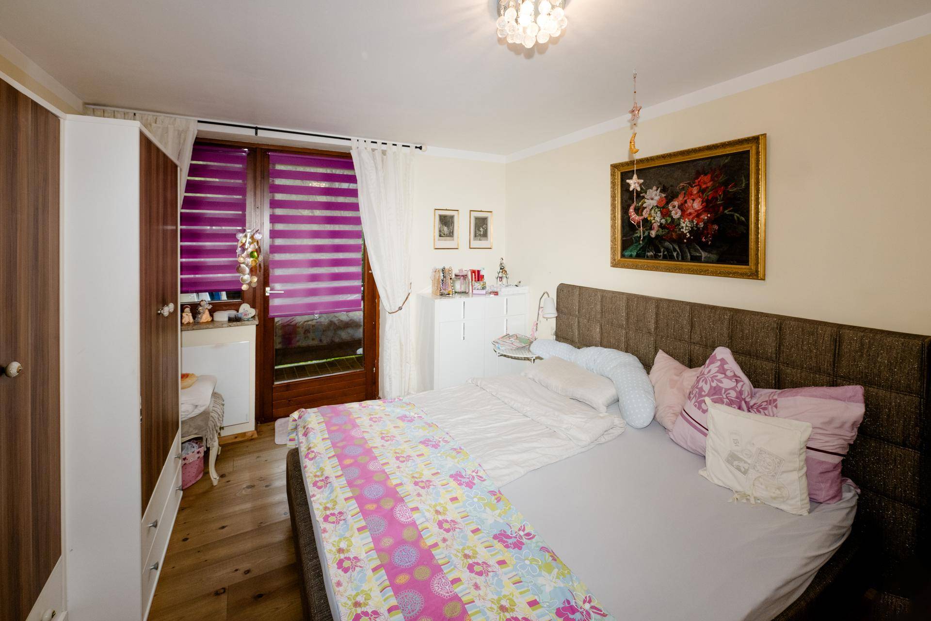 Komfortables Schlafzimmer mit Doppelbett, Kleiderschrank und Zugang zu einem Balkon oder Terrasse.