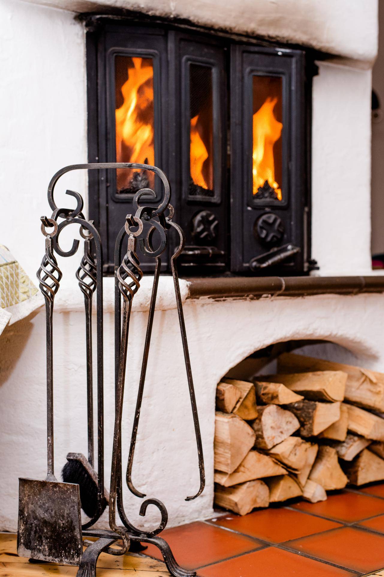 Nahaufnahme des brennenden Kachelofens mit Holzscheiten, der Wärme und Gemütlichkeit spendet.