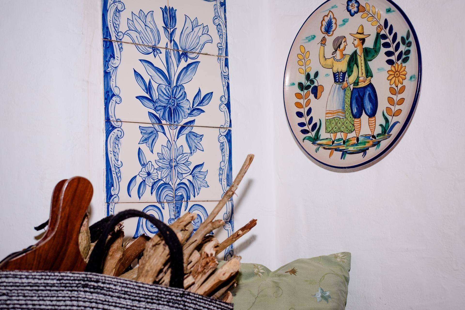 Dekorative blaue Fliesen am Kachelofen und ein traditioneller Teller schmücken den Wohnbereich.