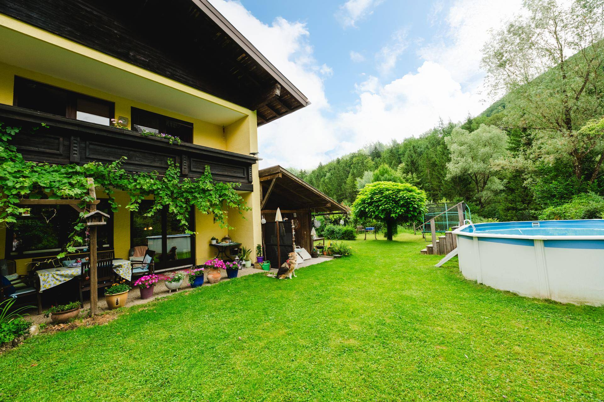 Weitläufiger Garten mit Rasenfläche, Pool und Blick auf die umliegende Berglandschaft.
