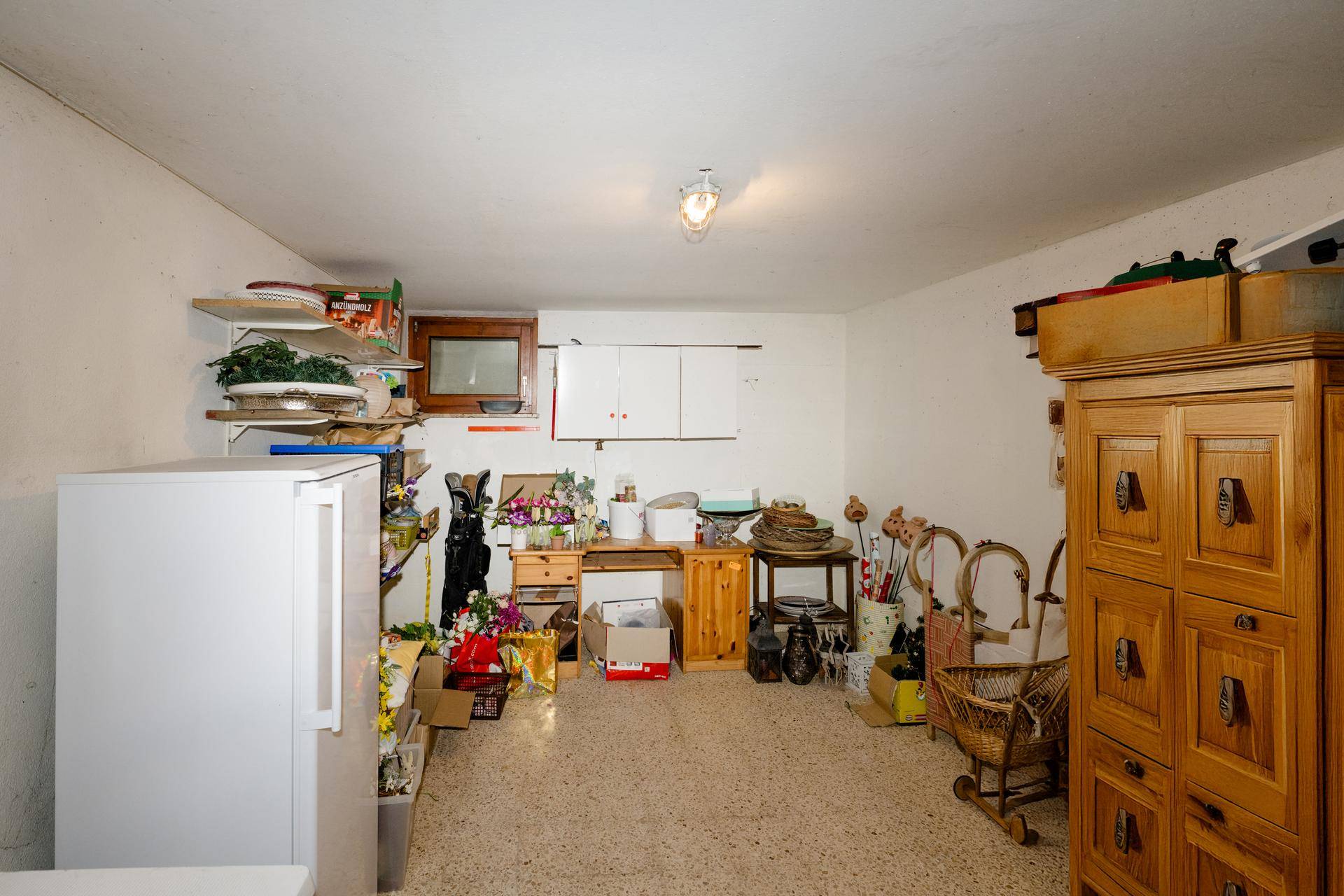 Geräumiger Abstellraum im Keller mit Regalen, Kühlschrank und viel Stauraum.