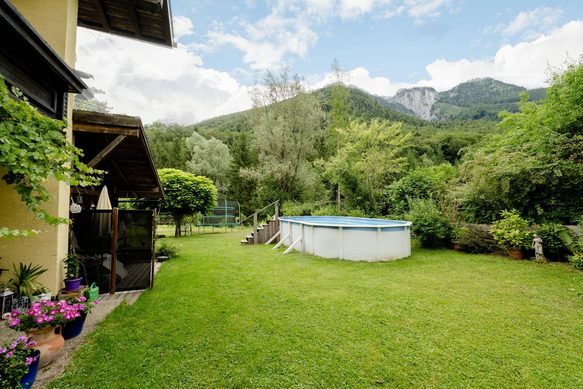 Großer Garten mit Pool, Trampolin und beeindruckendem Bergblick, ideal für Freizeitaktivitäten.