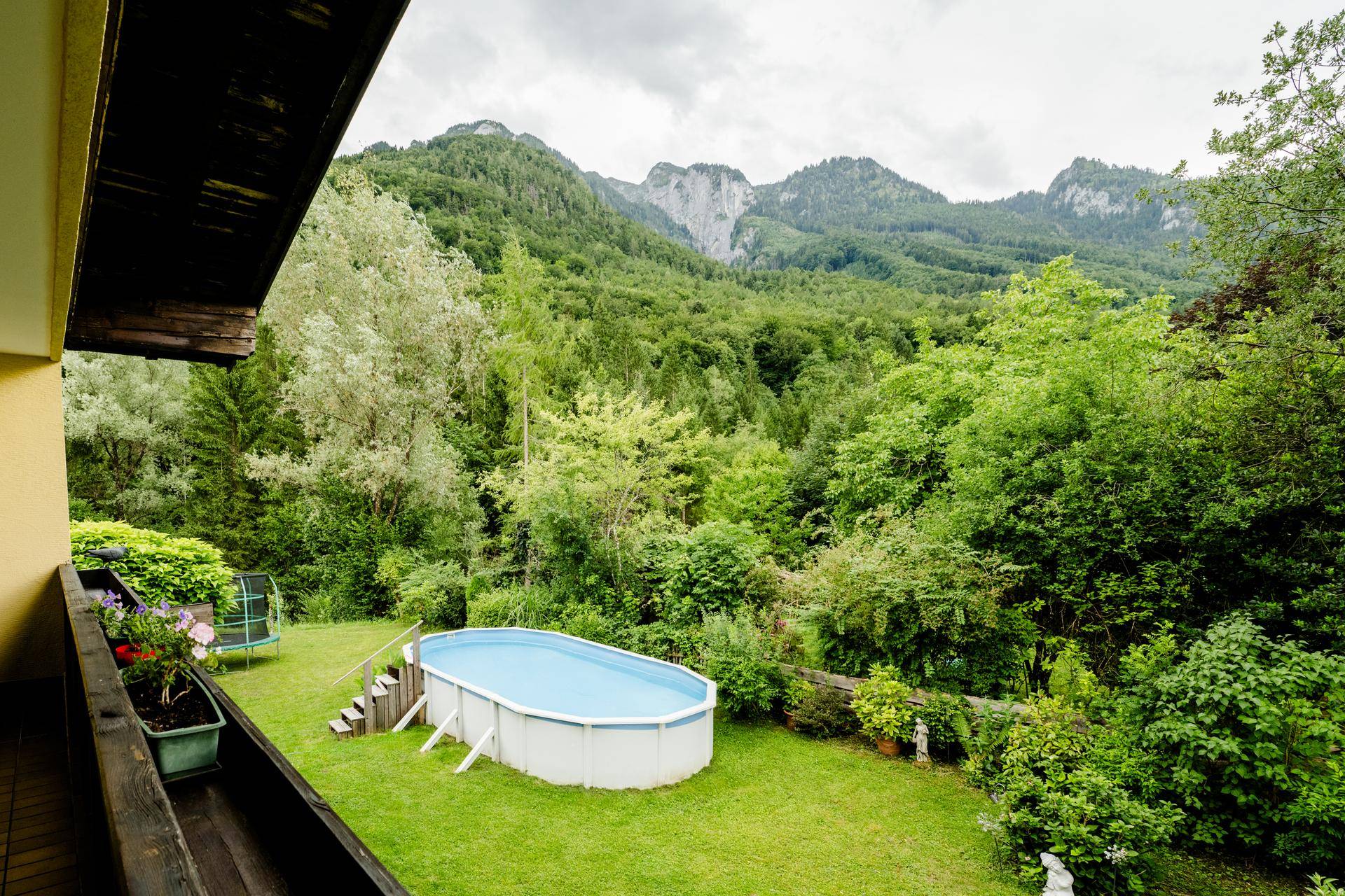 Panoramablick vom Balkon auf den Garten mit Pool und die majestätischen Berge im Hintergrund.