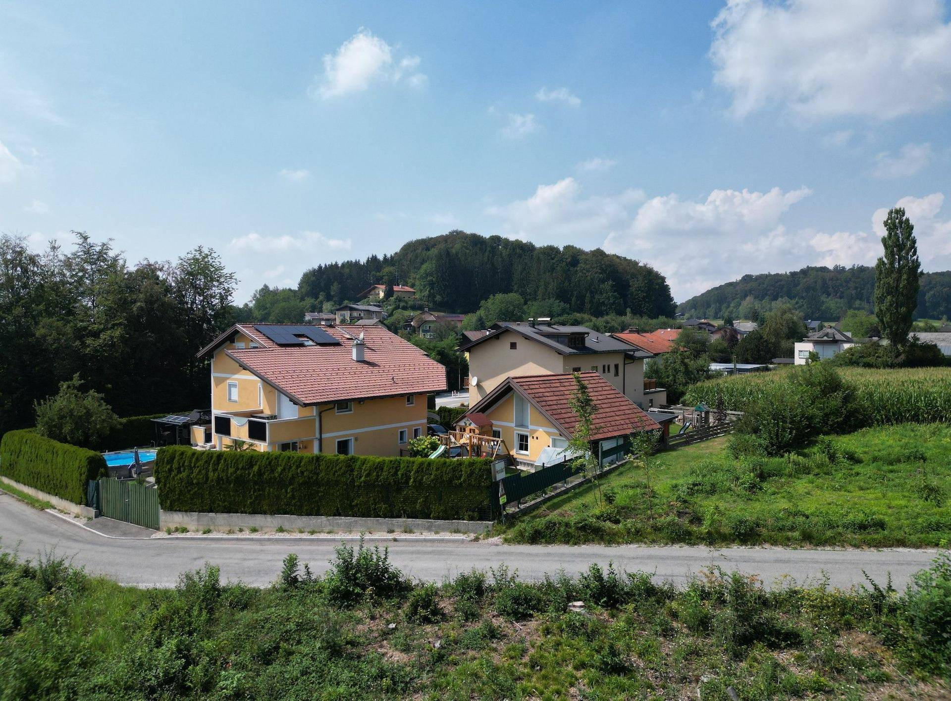 Mehrere Wohnhäuser in einer grünen, ländlichen Umgebung mit einem Pool und Solaranlagen auf dem Dach.