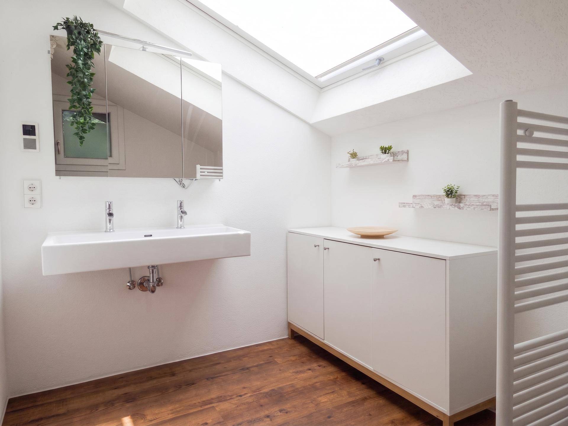 Modernes Badezimmer im Dachgeschoss mit Doppelwaschbecken, Holzboden und Dachfenster.