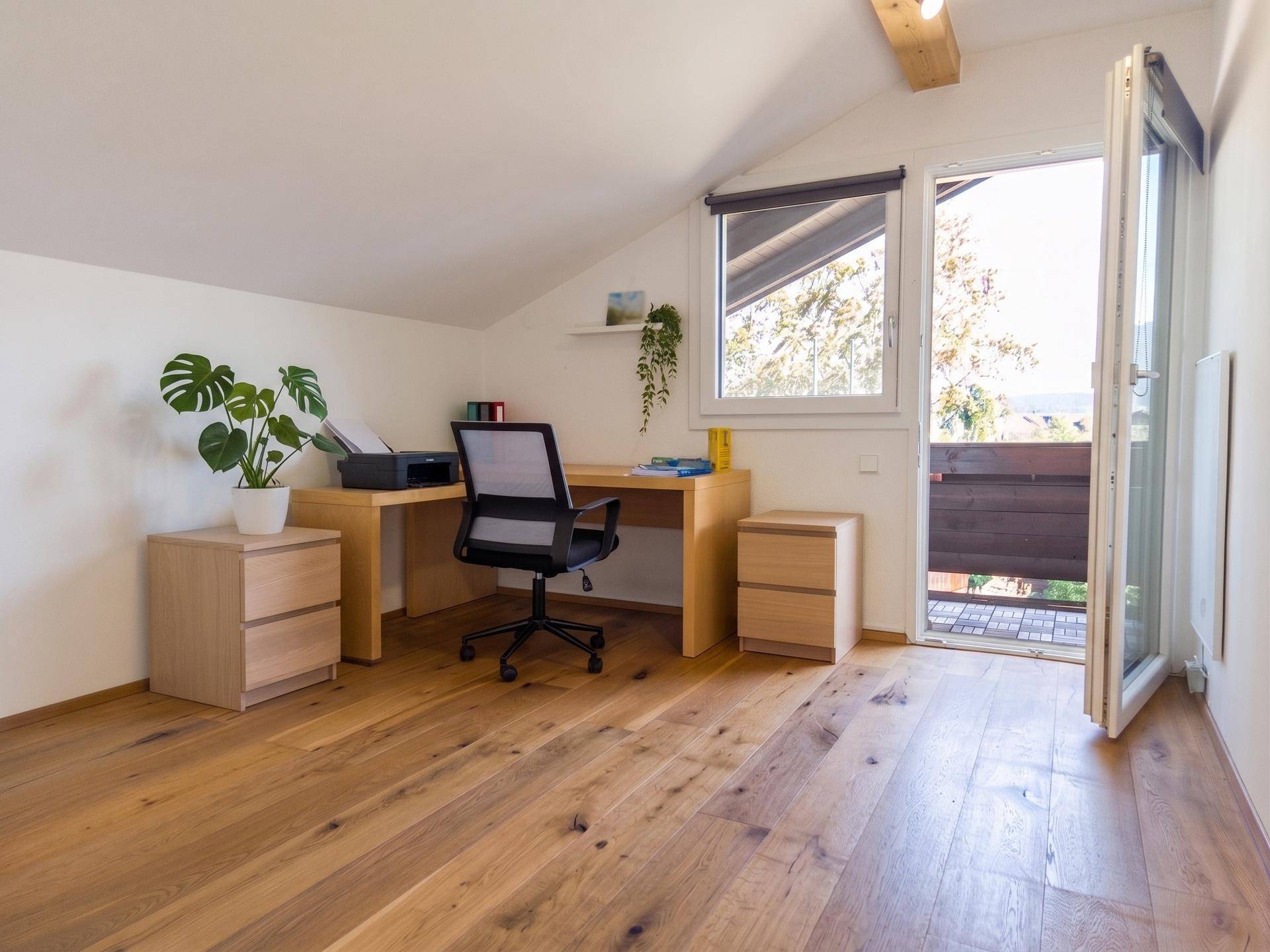 Helles Arbeitszimmer im Dachgeschoss mit Holzboden und Zugang zum Balkon.