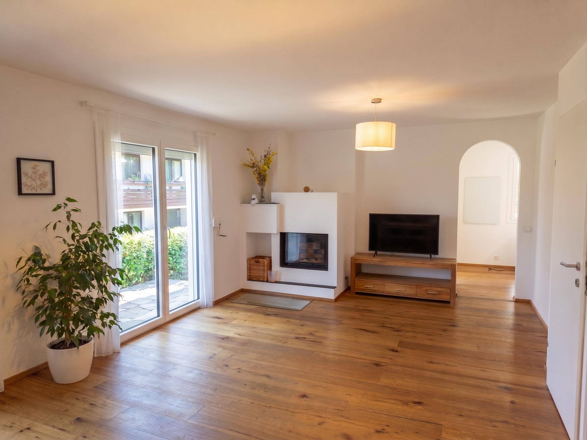 Geräumiges Wohnzimmer mit Holzboden, Kamin und Zugang zur Terrasse.
