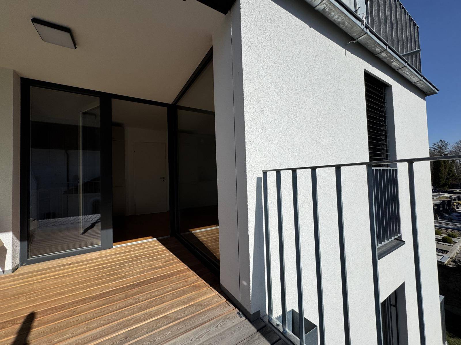 Moderne Terrasse mit Holzboden und schwarzem Geländer, die einen schönen Außenbereich bietet.